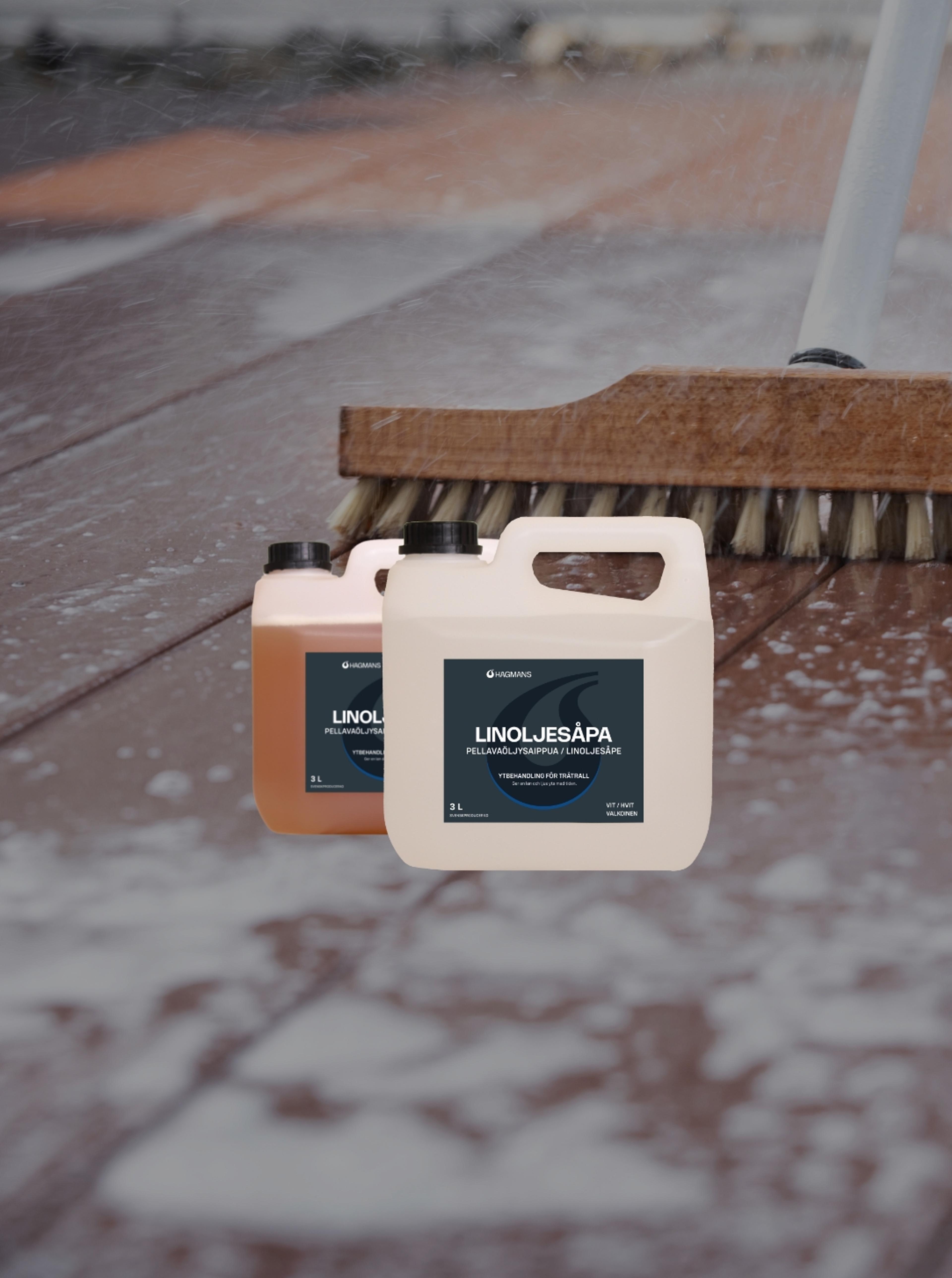 Two bottles of "Linoljesåpa" cleaner sit on a wet wooden deck being scrubbed with a brush.