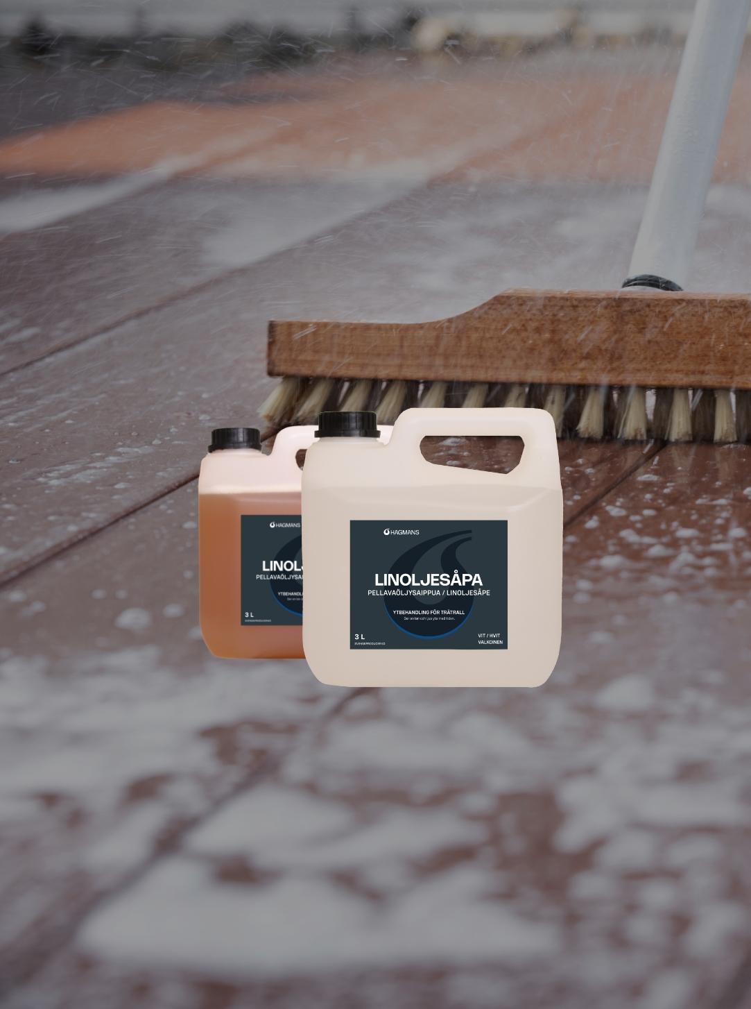 Two bottles of "Linoljesåpa" cleaner sit on a wet wooden deck being scrubbed with a brush.