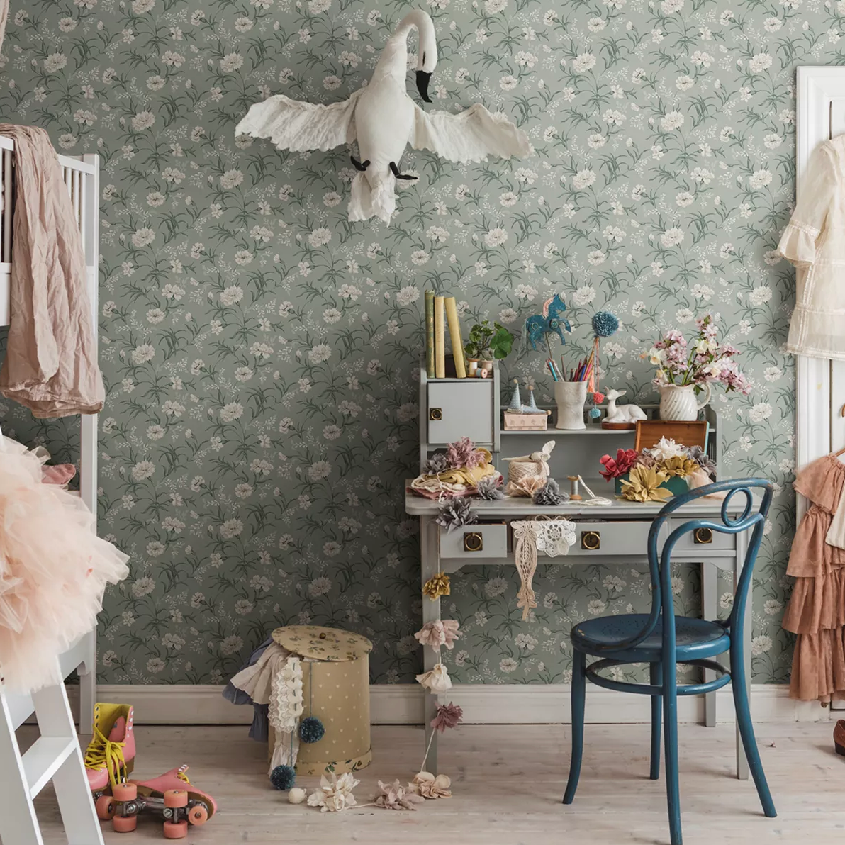 Whimsical child's room with green floral wallpaper, a fabric swan, craft desk, and pink roller skates.