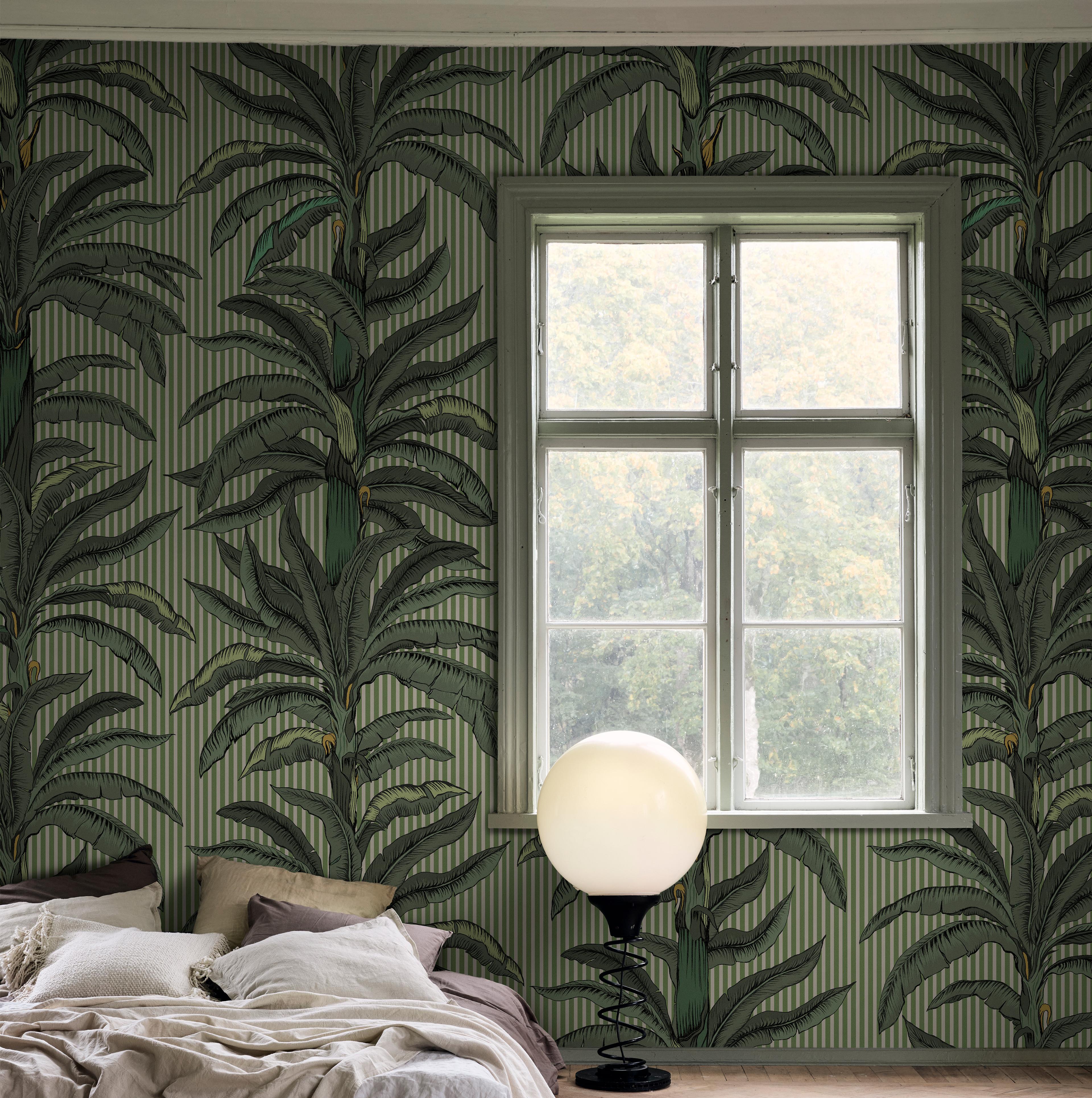 Room with green palm tree and striped wallpaper, a window, a bed, and a spherical floor lamp.