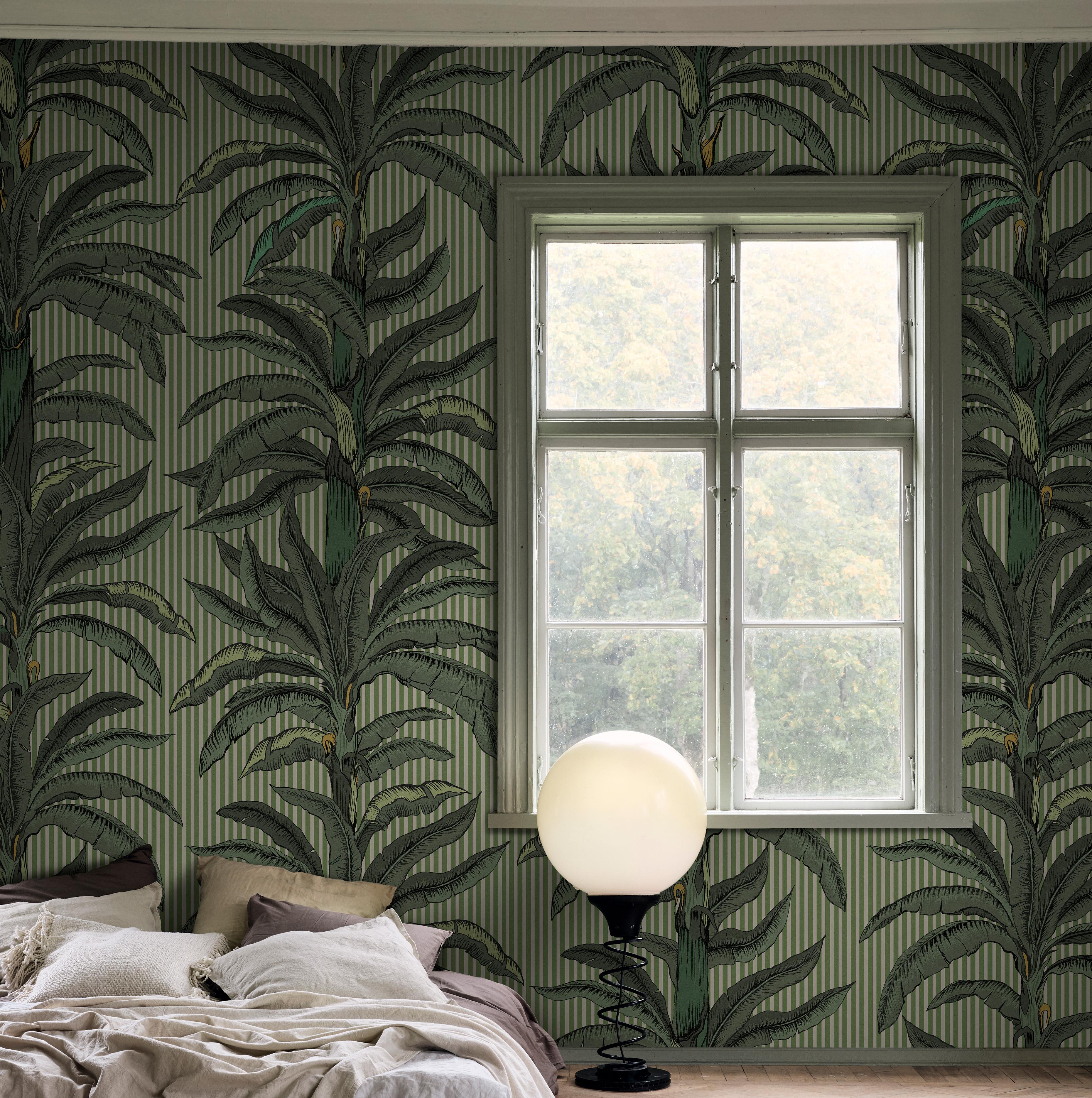 Room with green palm tree and striped wallpaper, a window, a bed, and a spherical floor lamp.