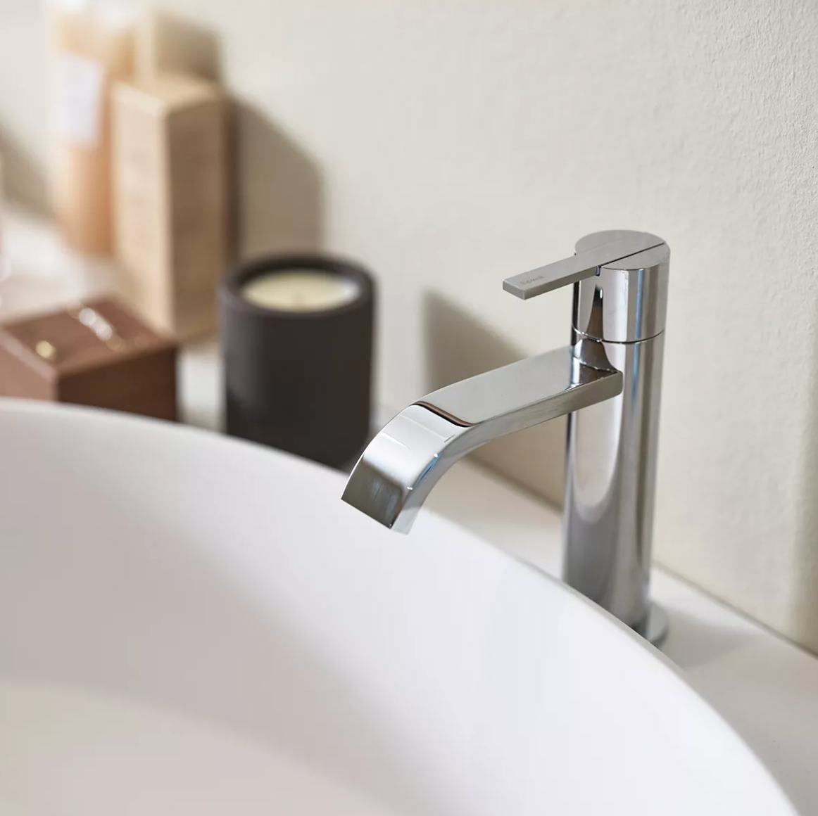 A modern chrome faucet over a white bathroom sink.