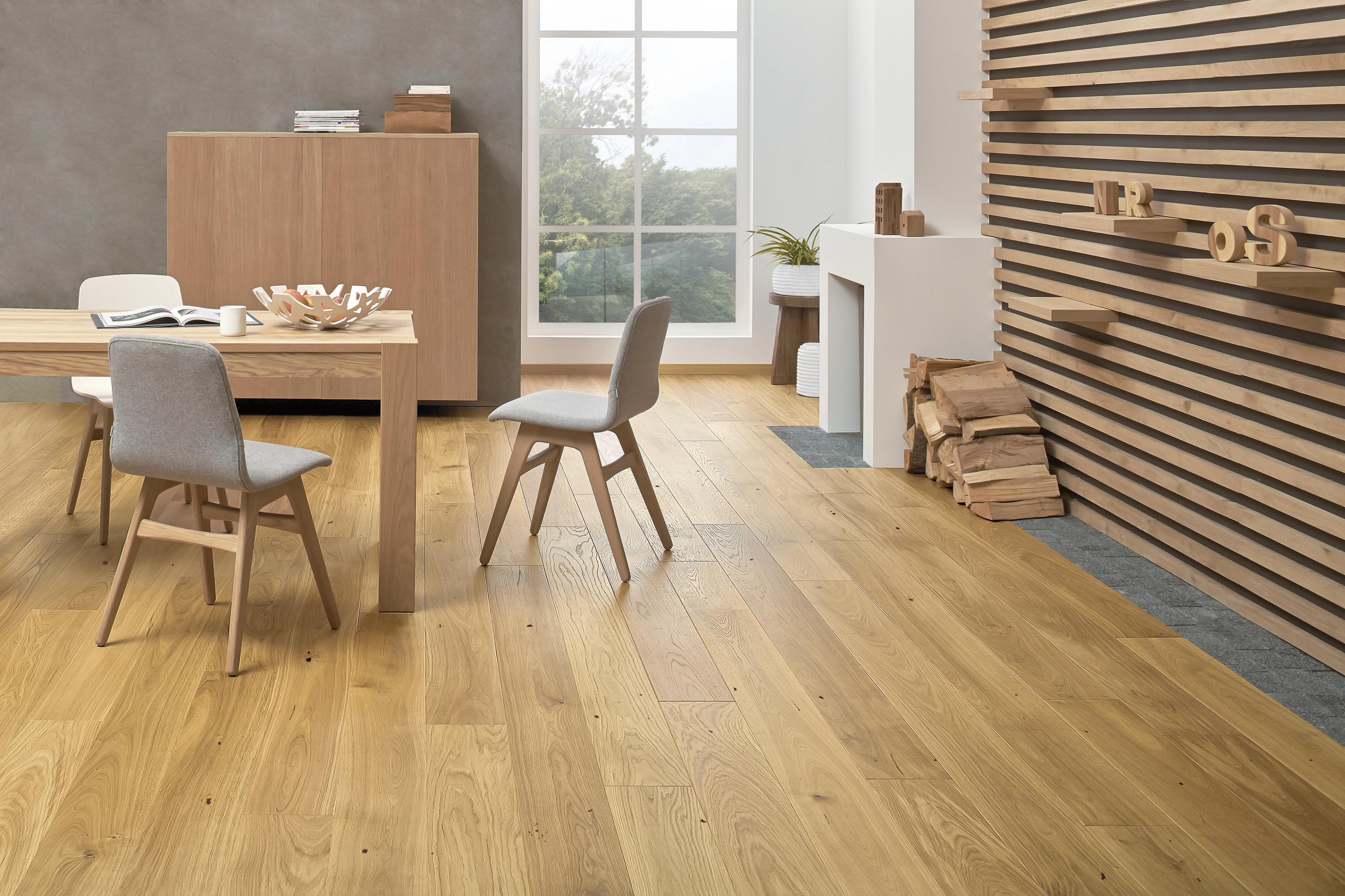 A modern dining and living space with light wood flooring, a wooden dining table and chairs, a cabinet, a decorative fireplace, and a slatted wood accent wall.
