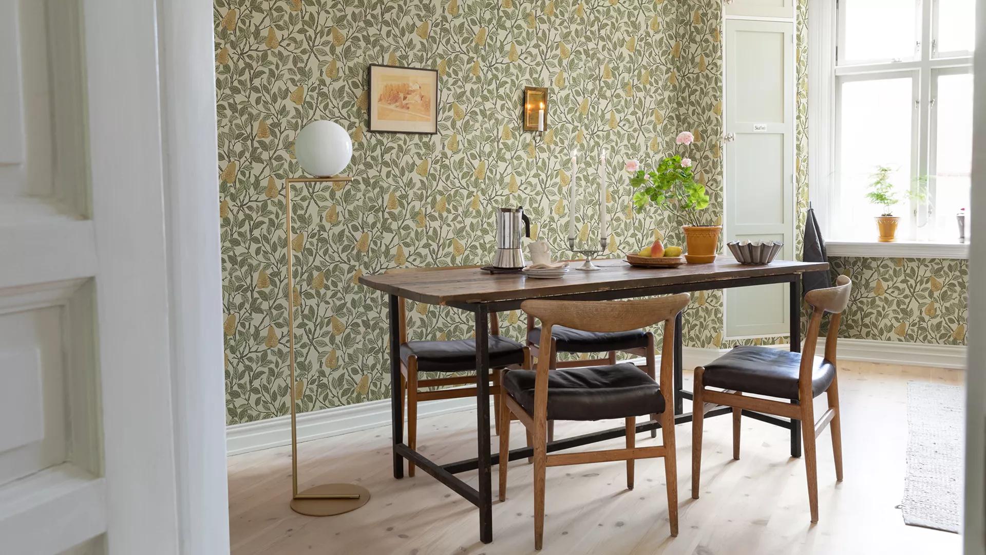 A dining room with green and yellow pear-patterned wallpaper, a wooden dining table with chairs, and a modern globe floor lamp.