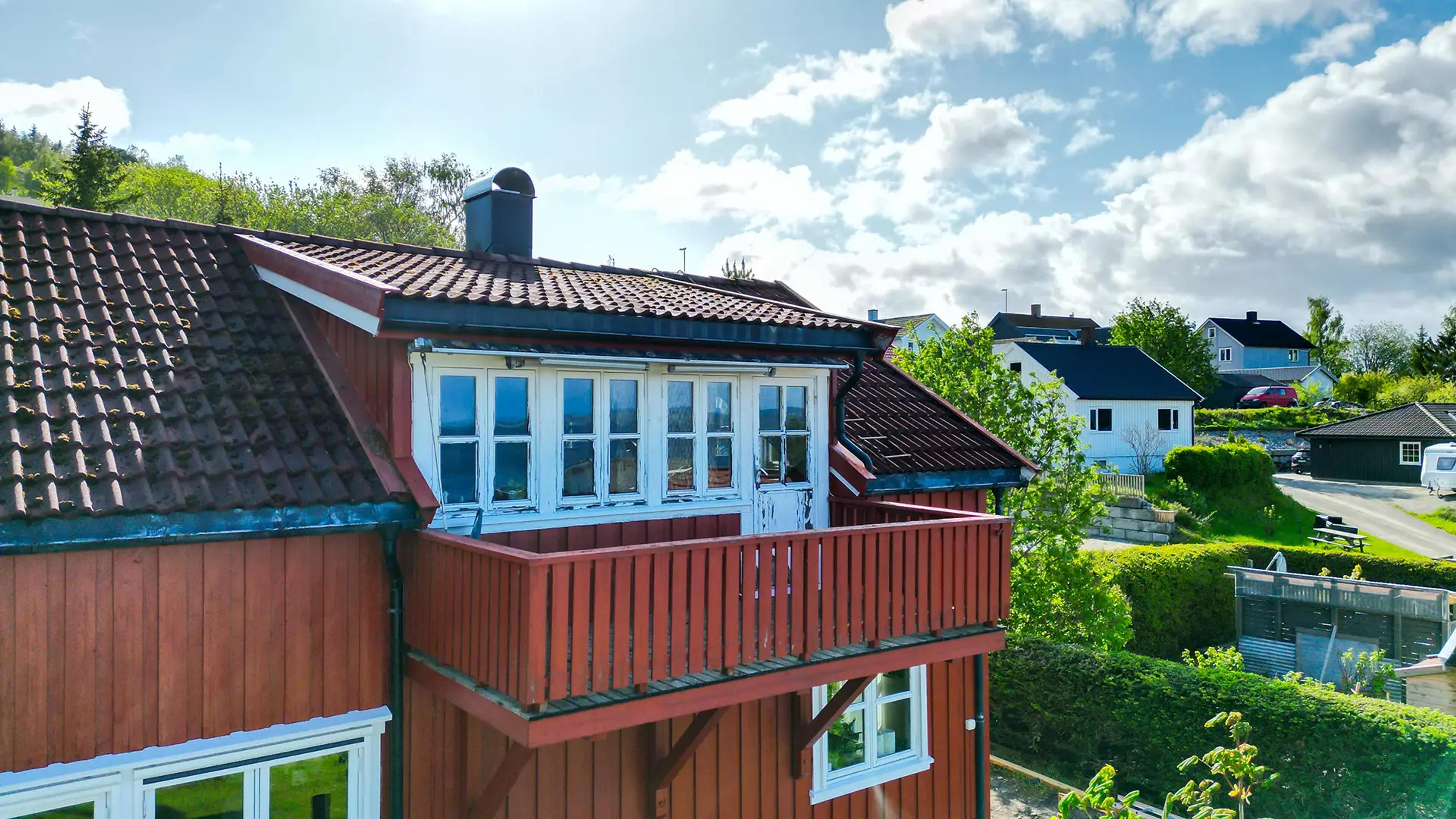 Et slitt rødt hus med en balkong