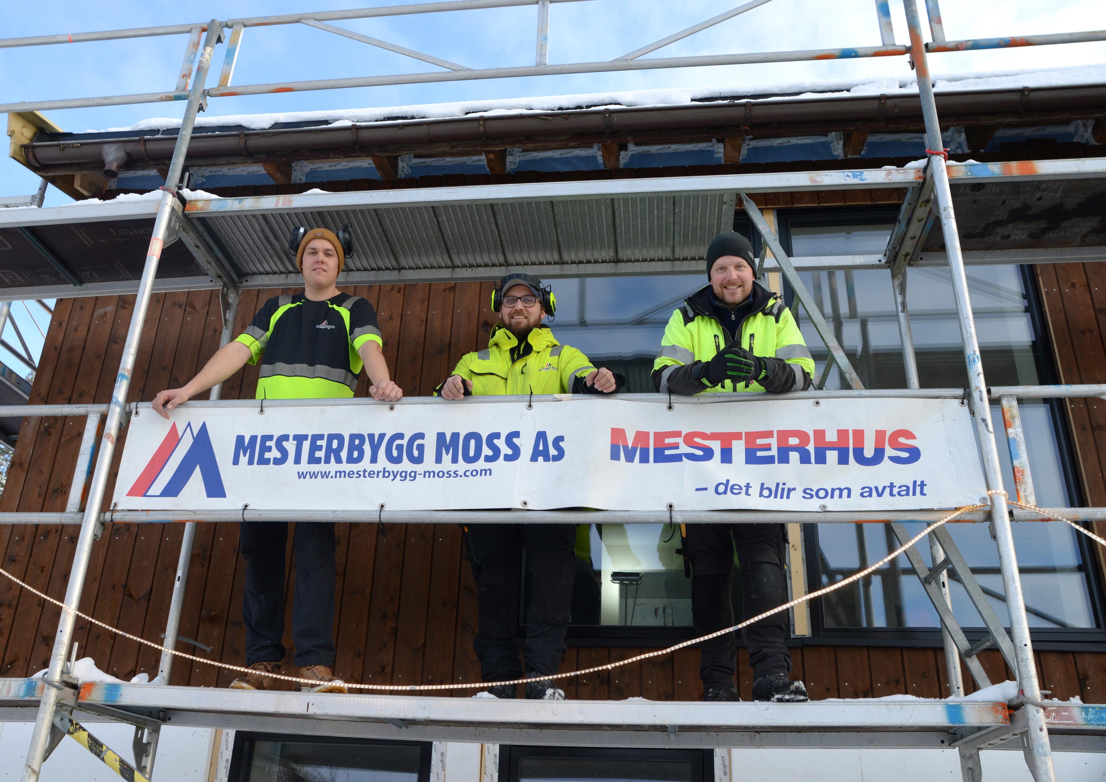 Tre arbeidere i stilas med logo