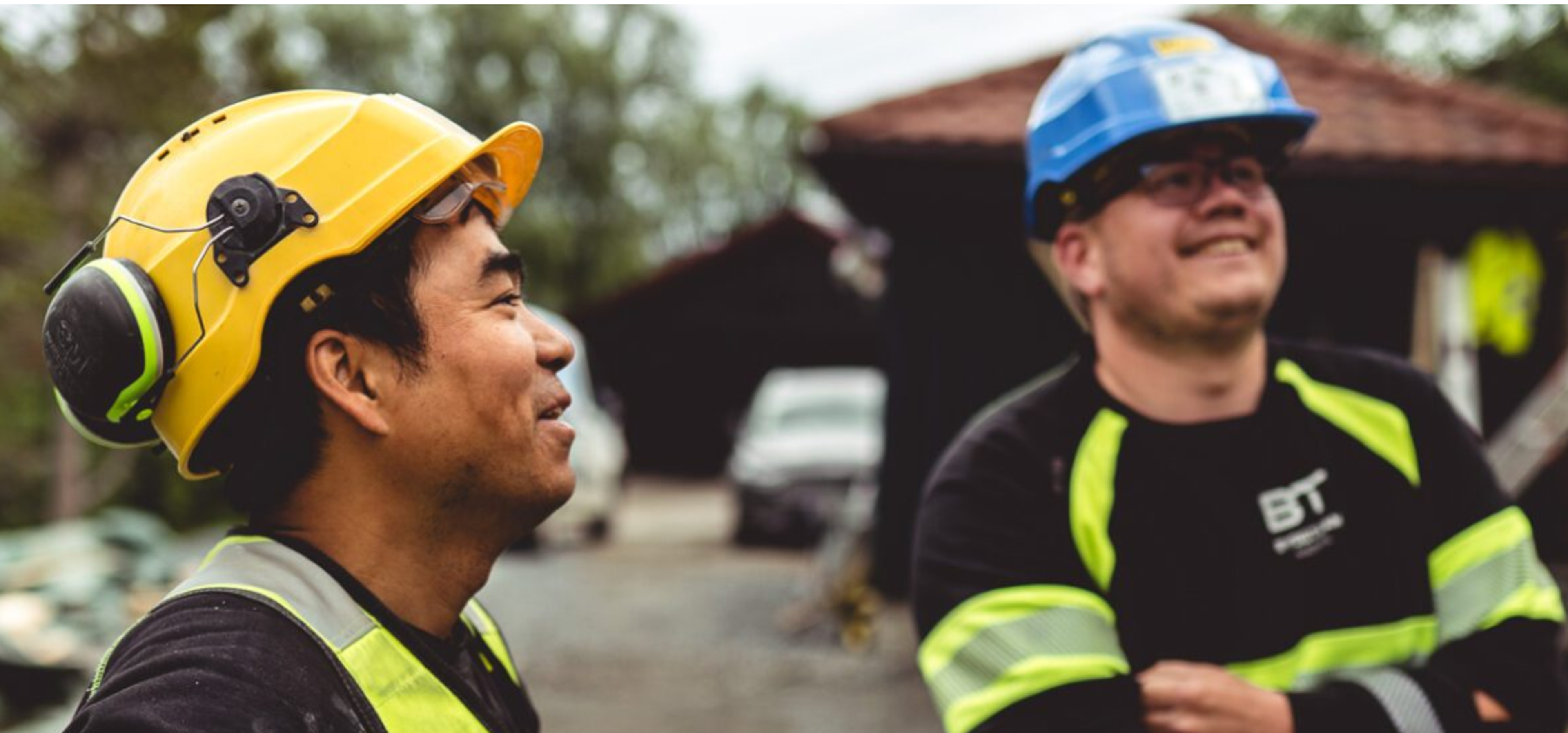To arbeidere med hjelm som ler