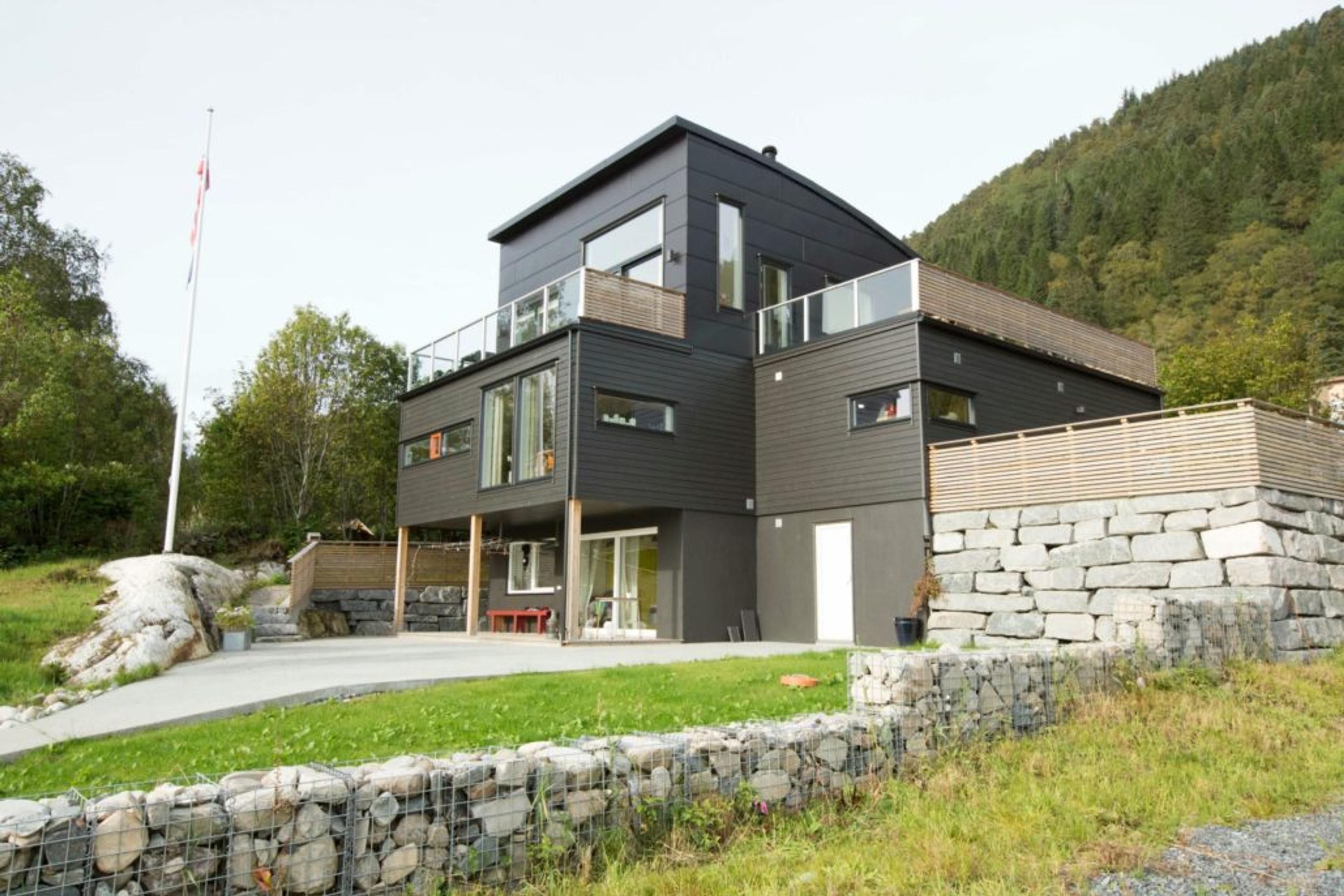 Svart hus på tre plan med balkong