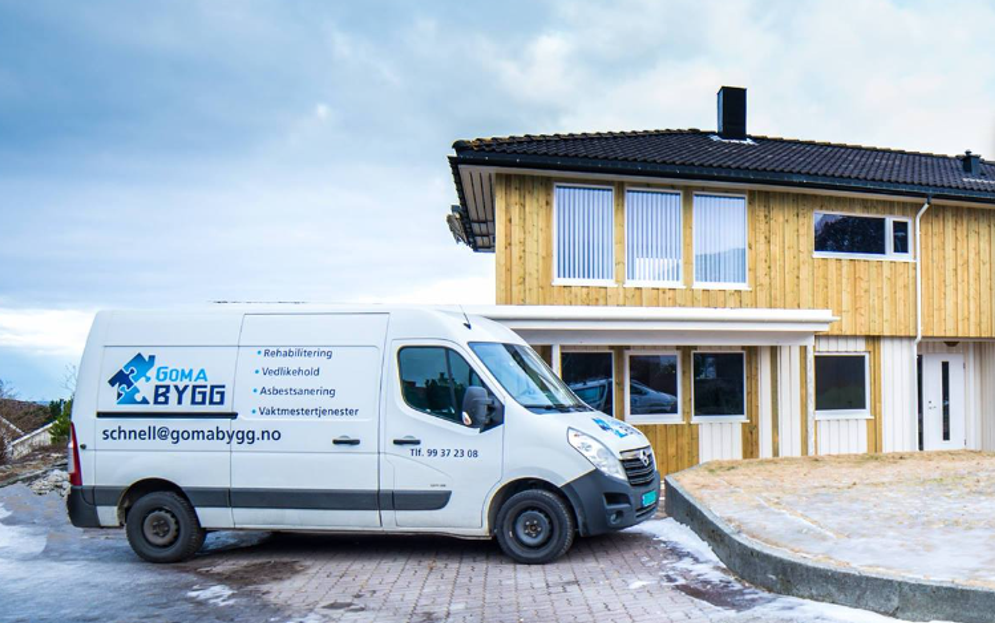 Hvit varebil med Goma Bygg AS logo foran hus