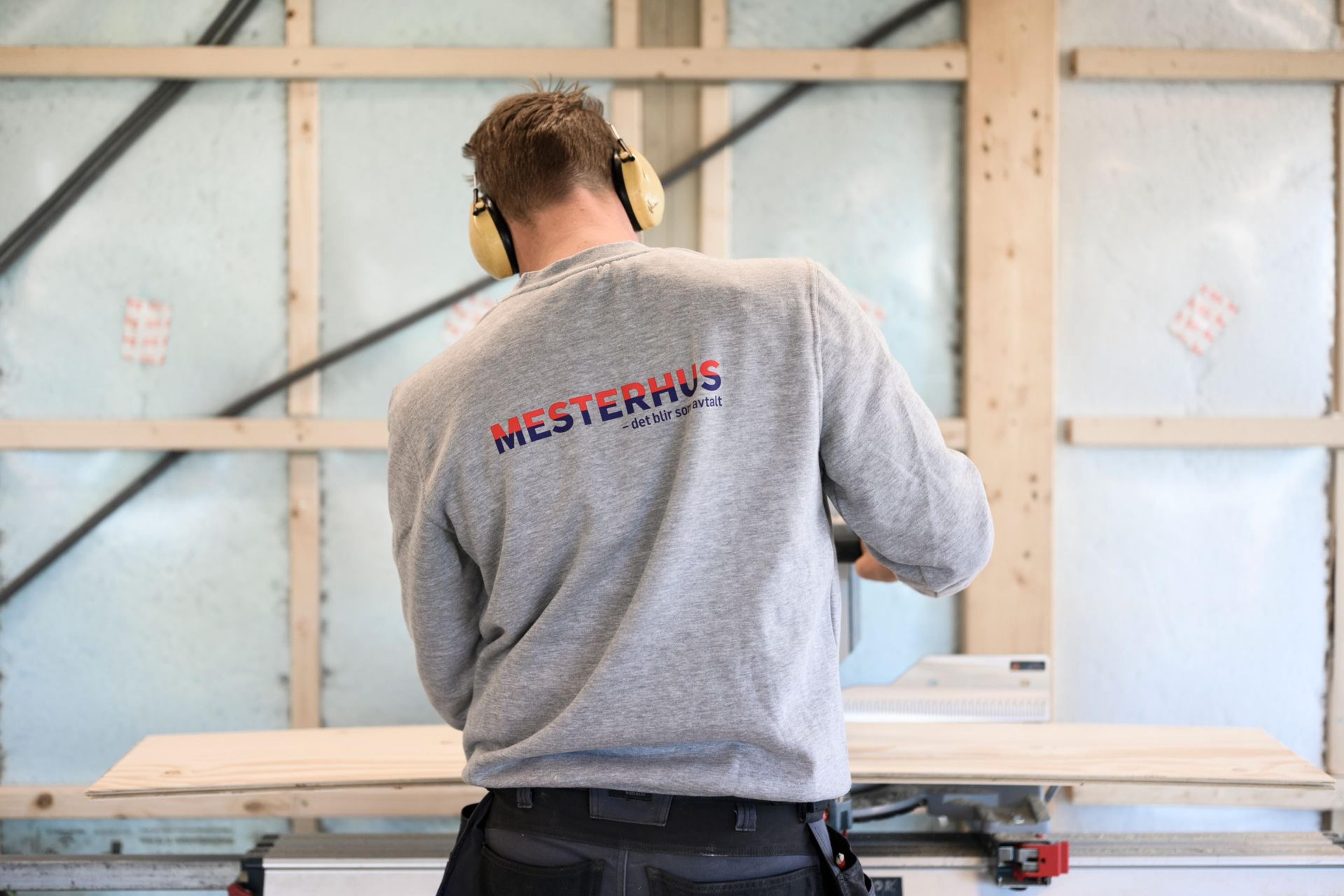 En tømrer på jobb med Mesterhus logo på ryggen