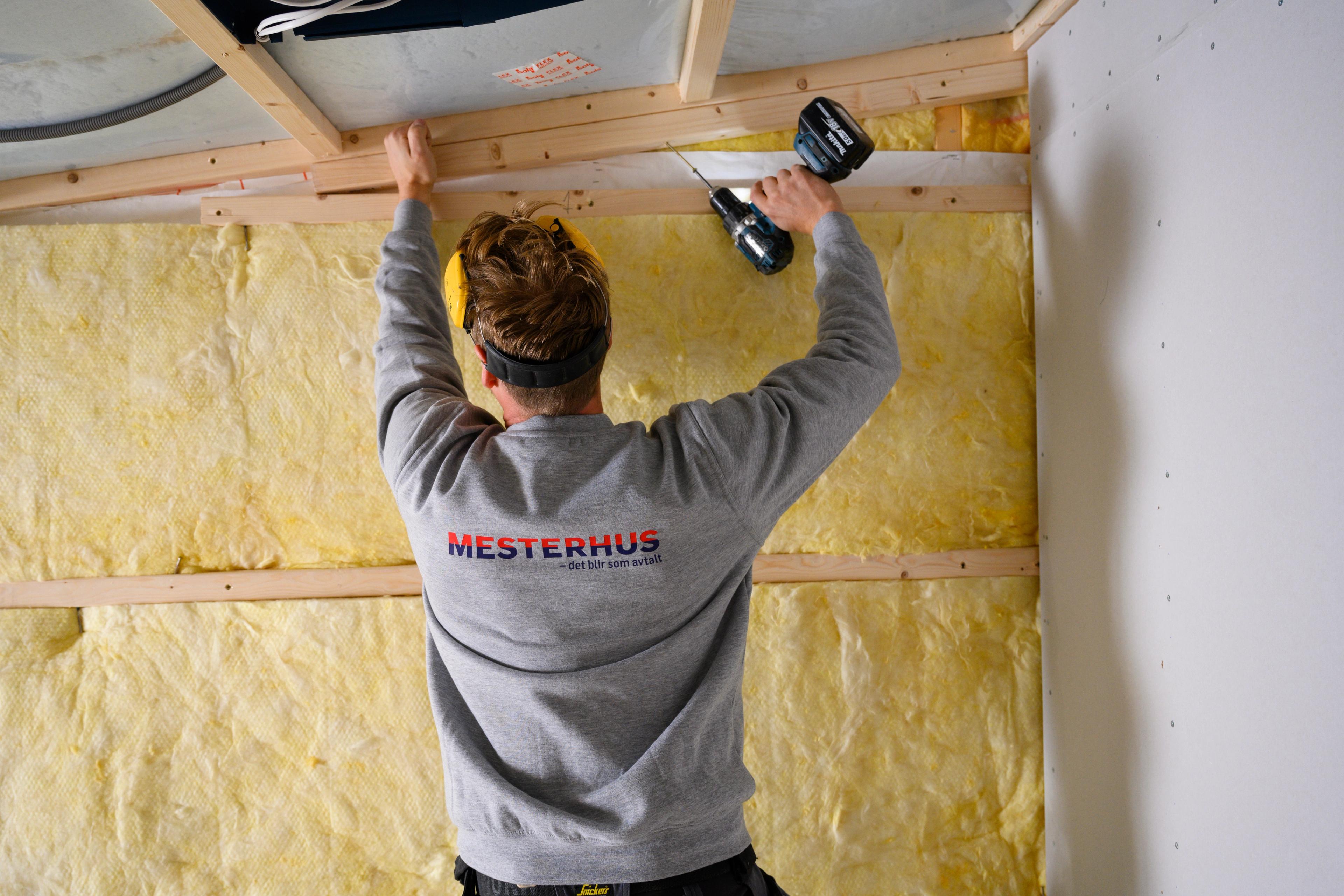 En tømrer på jobb med Mesterhus logo på ryggen