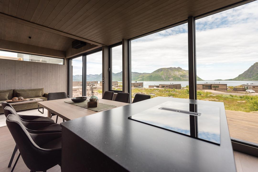 En stue med vinduer fra gulv til tak med utsikt over havet