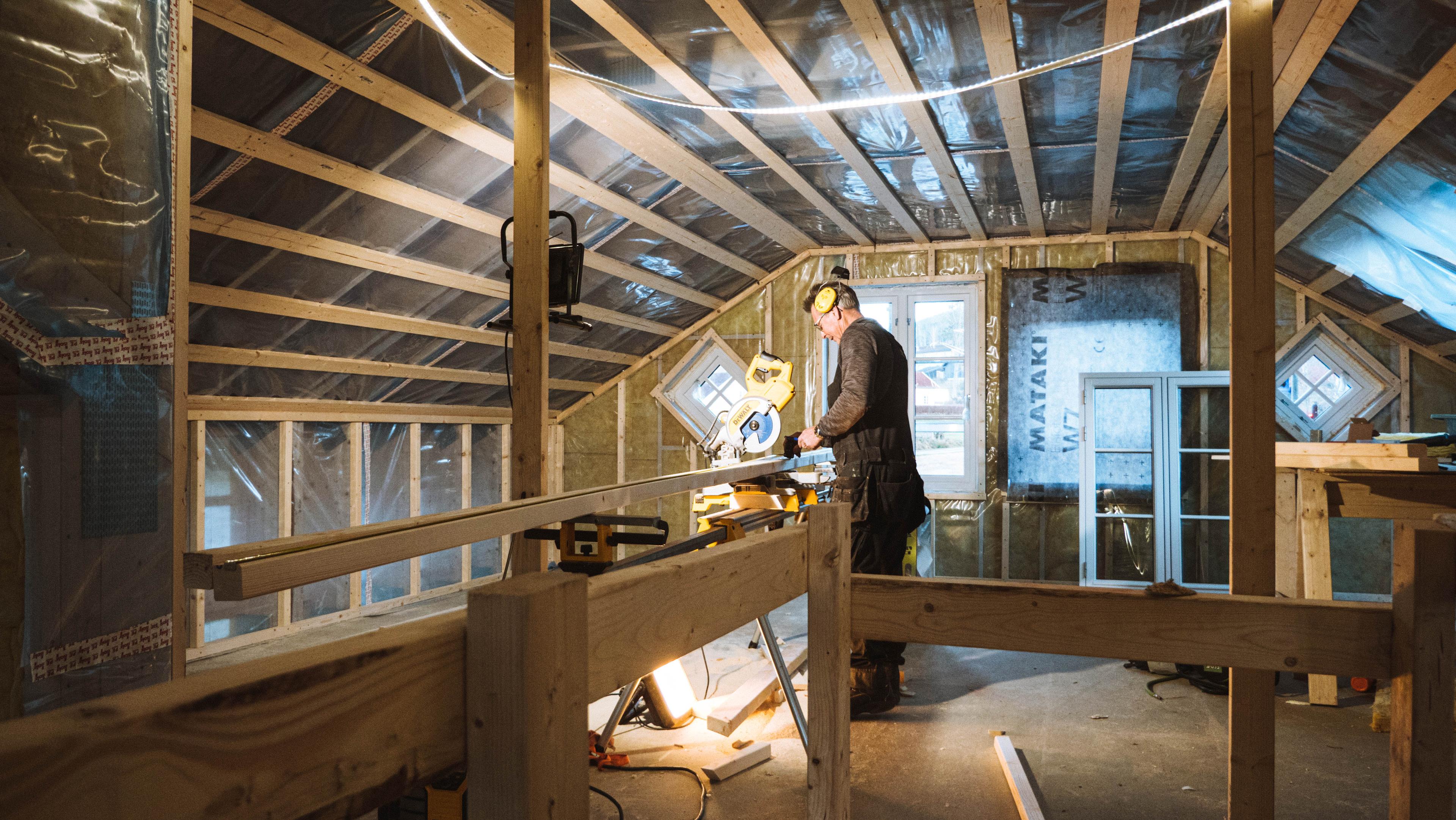 Arbeider som jobber med elektronisk sag på byggeprosjekt