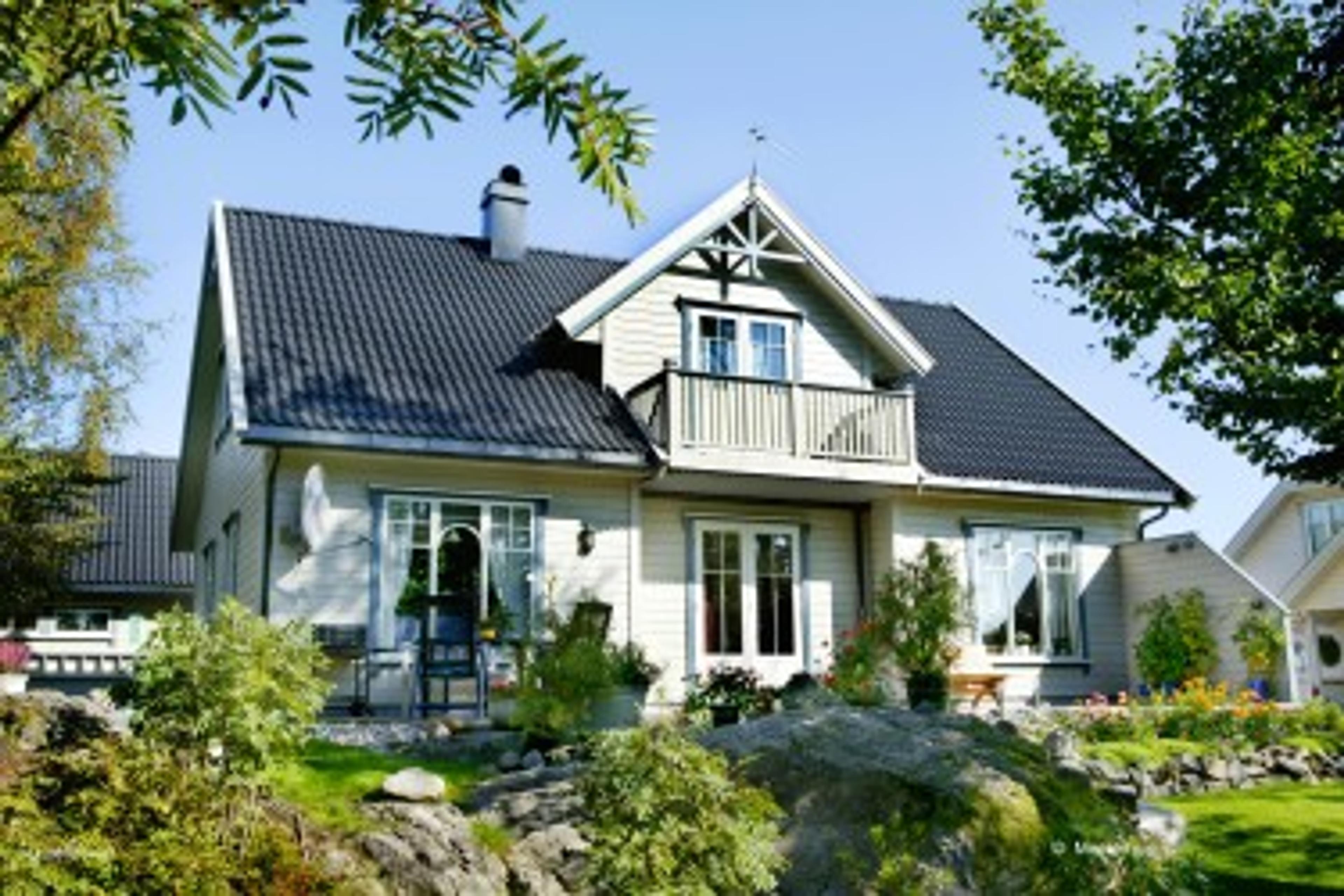 Hvit enebolig med balkong og hage
