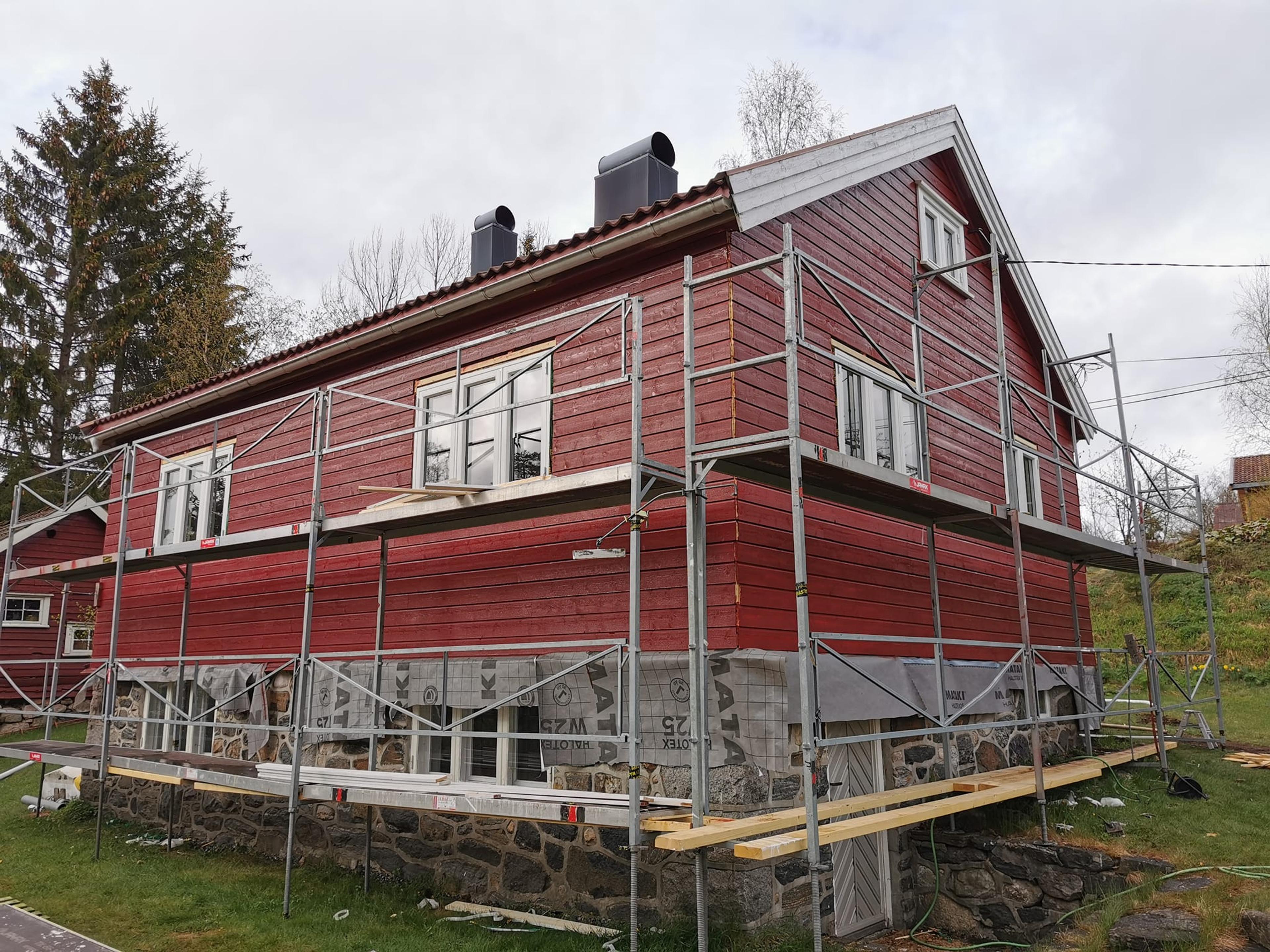 Rødt hus under rehabilitering med stilas rundt