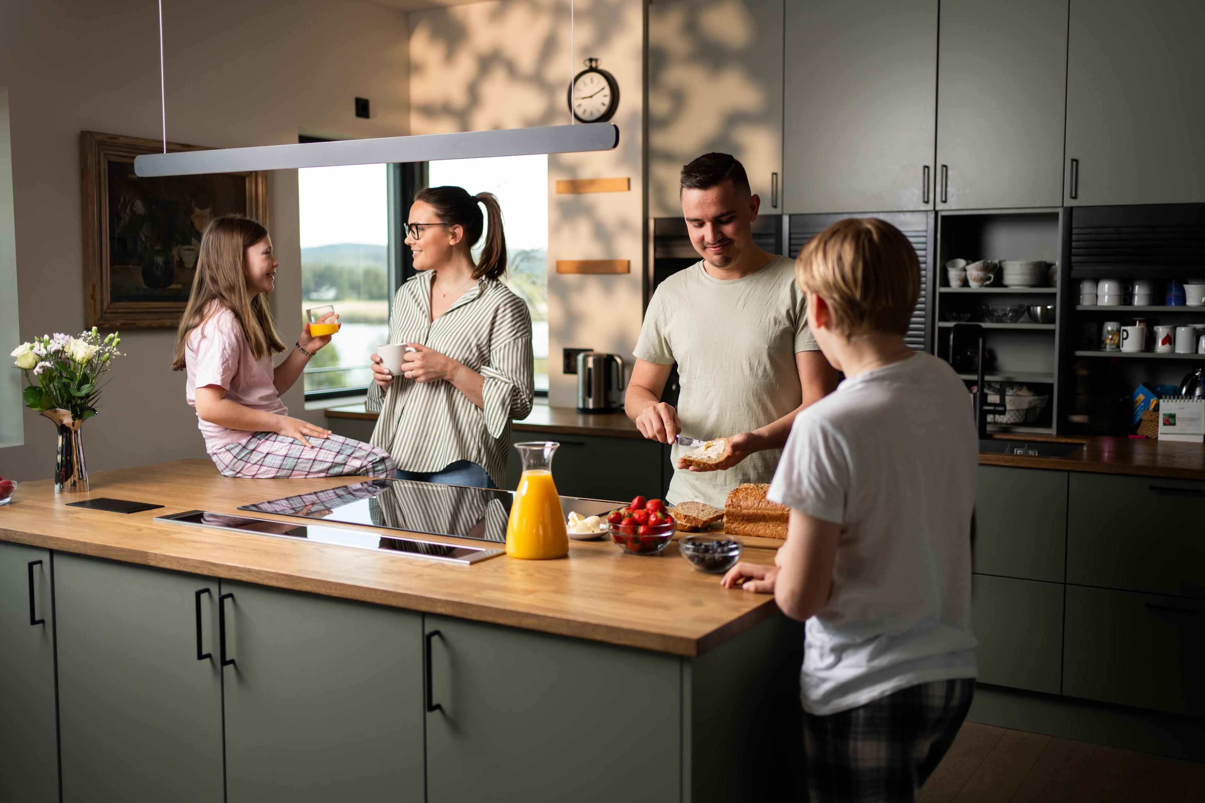 En familie på kjøkkenet som smiler og smører seg litt mat