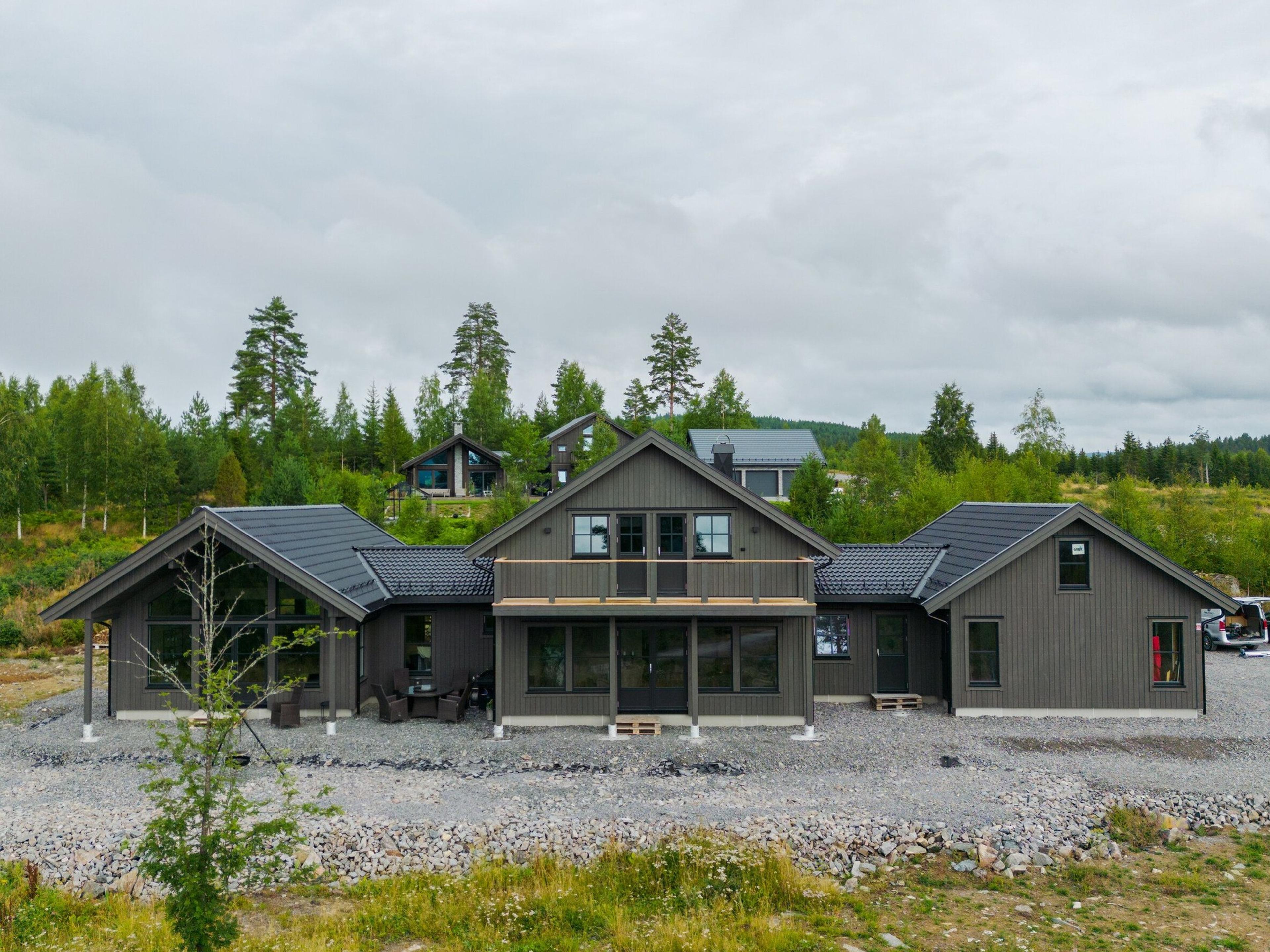 Stor svart hytte med skog i bakgrunn