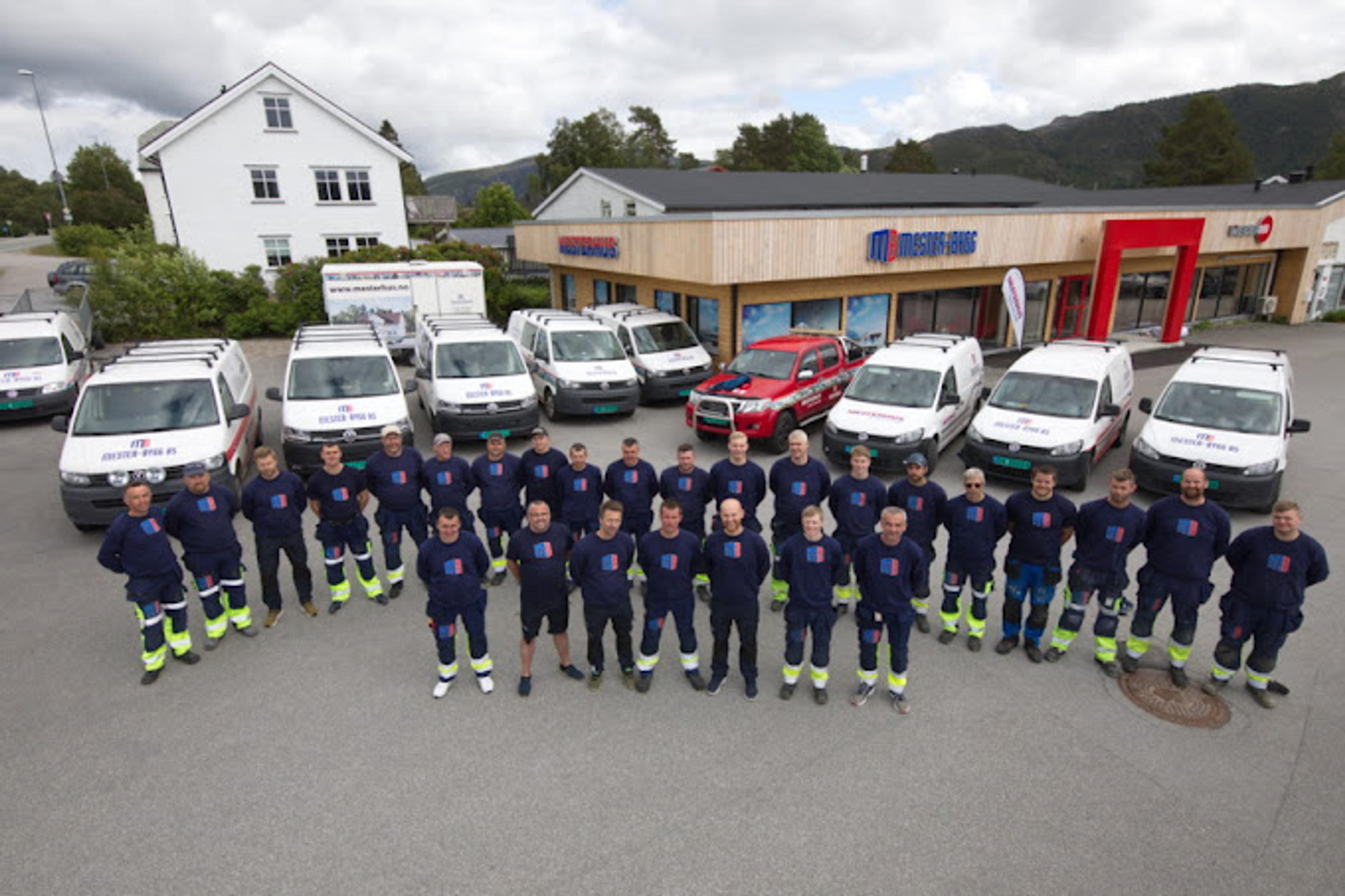 Ansatte gruppebilde med firmabiler bak dem