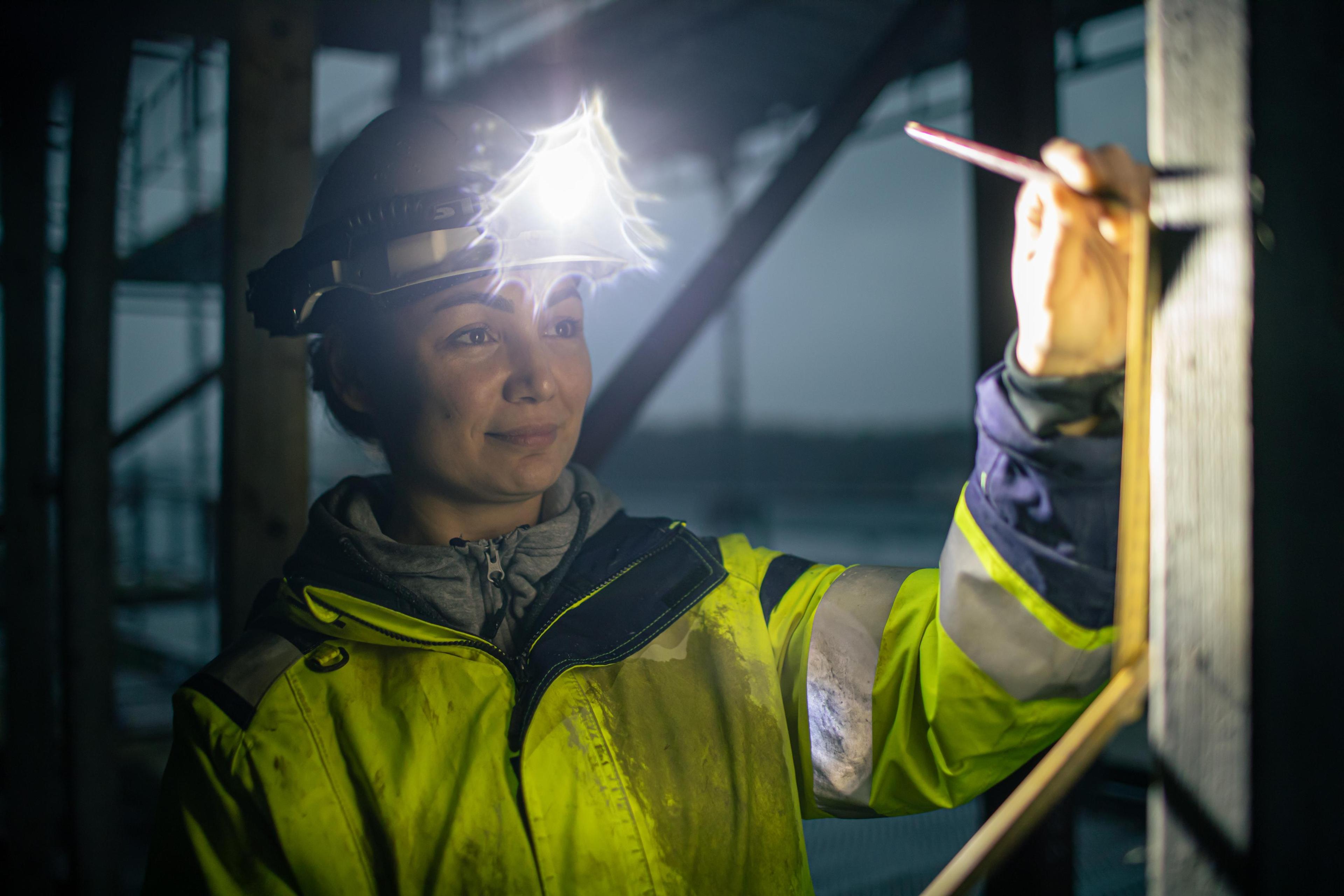 En dame med hodelykt og tar mål