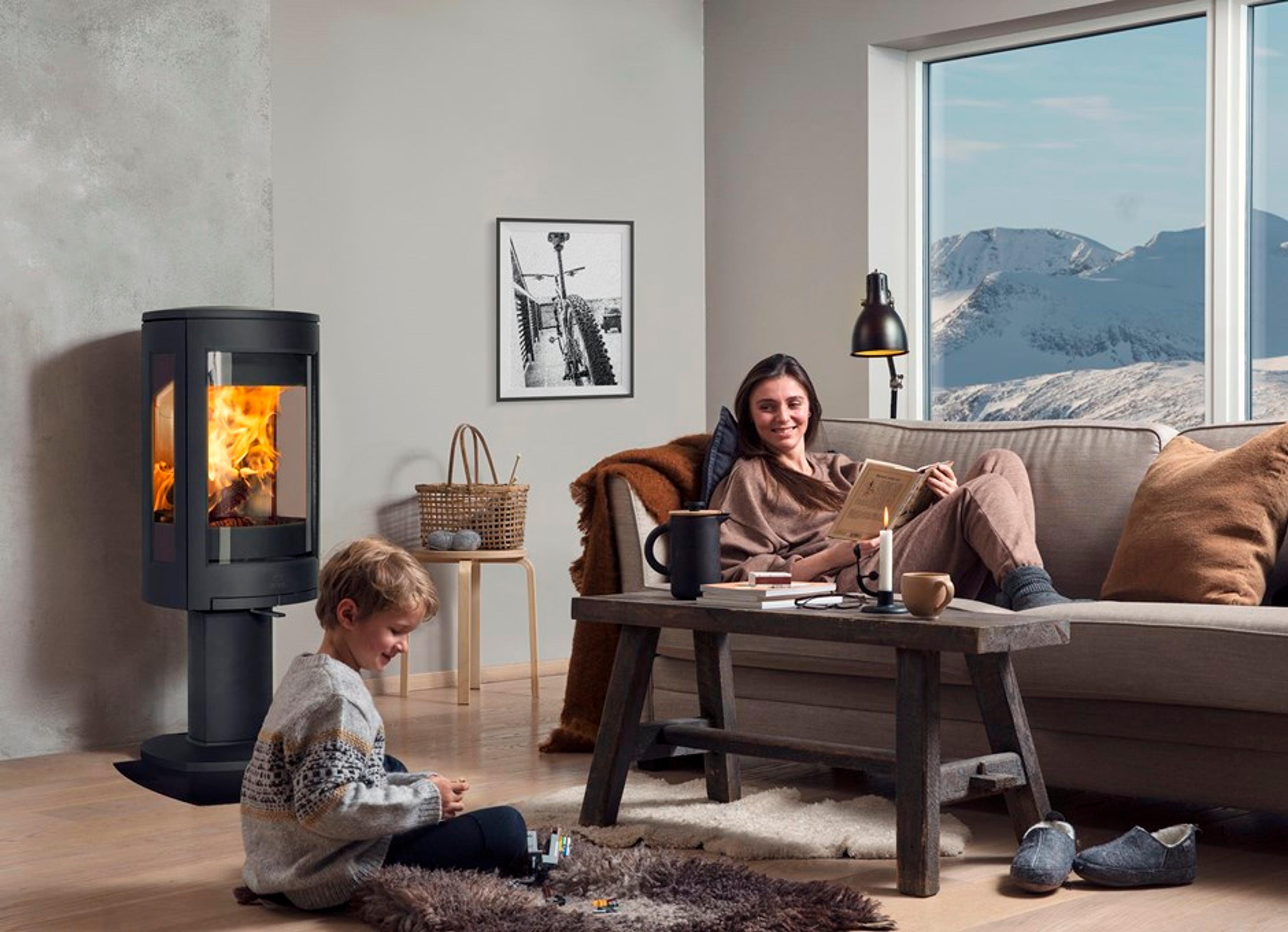 Mor og barn koser seg i stuen med peisovn