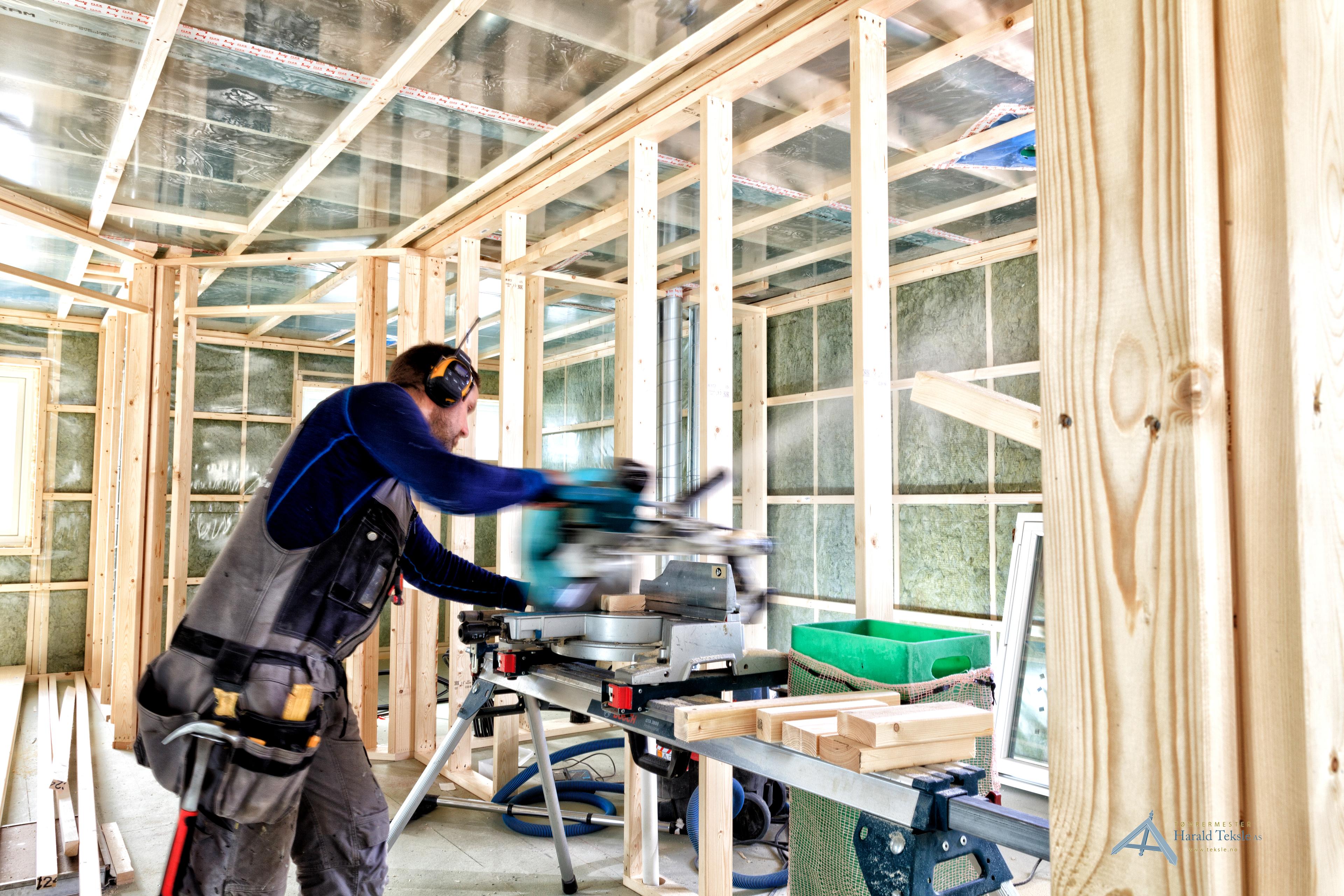 Tømrer som bruker kappsag inne i et hus