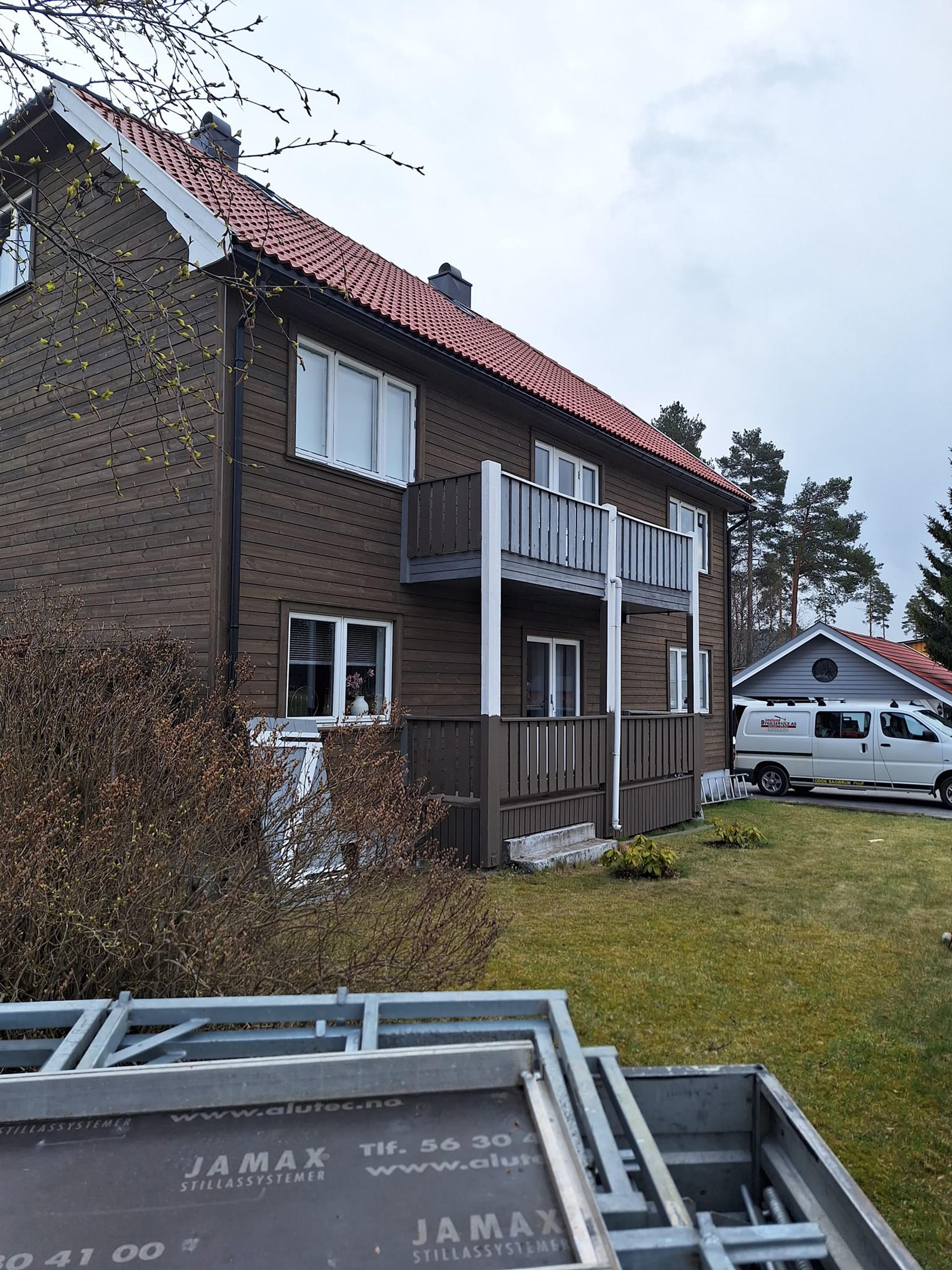 Brun enebolig med balkong og gressplen