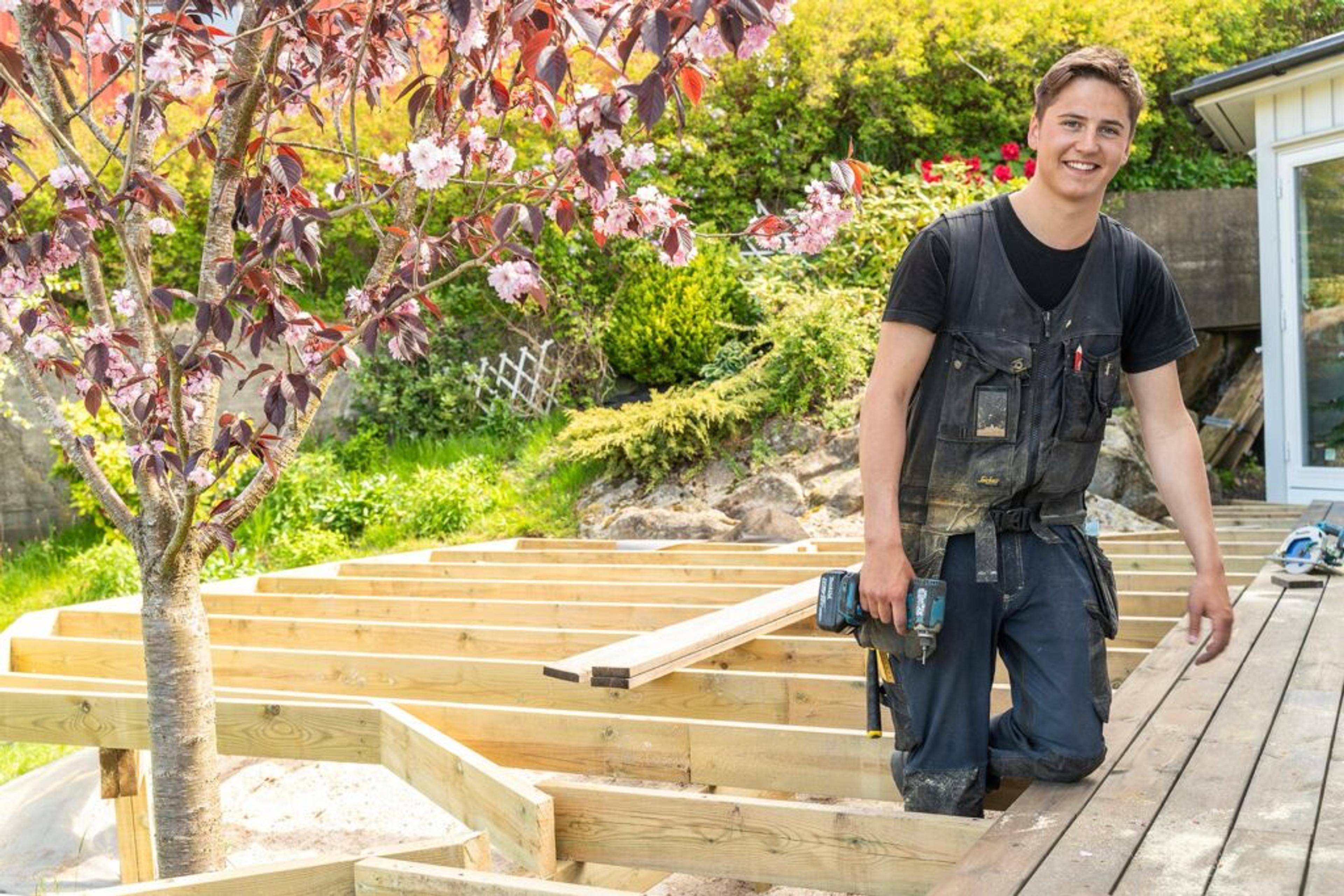 Arbeider som smiler og jobber med veranda