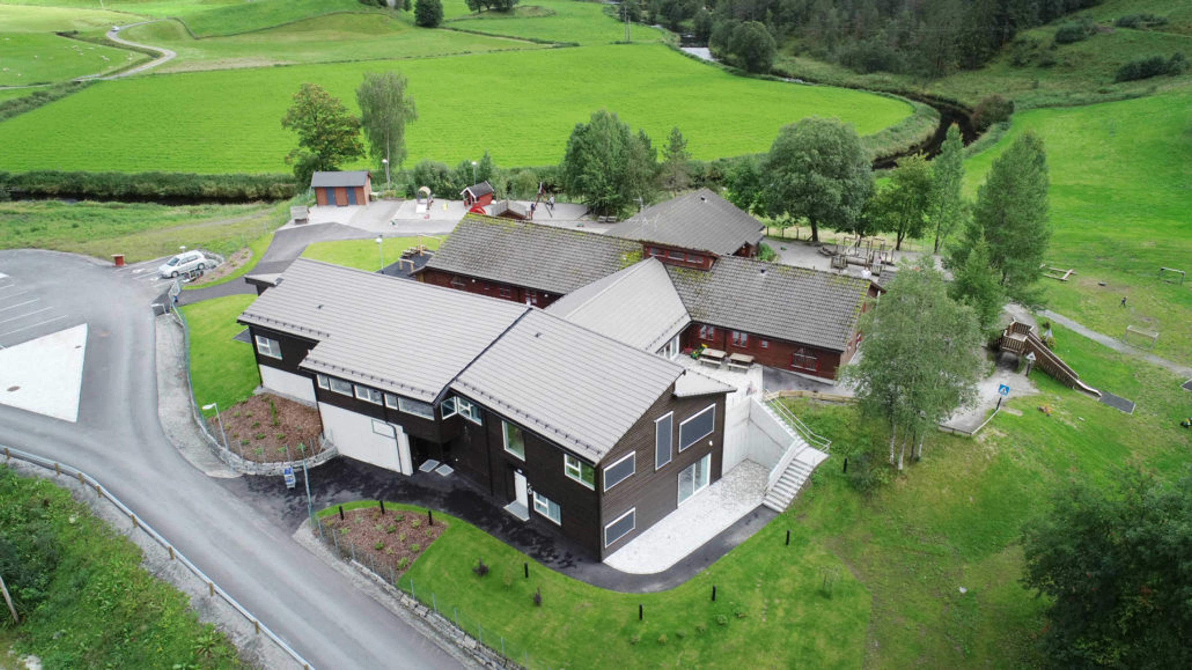 Brun barnehage sett ovenfra med åker i bakgrunn