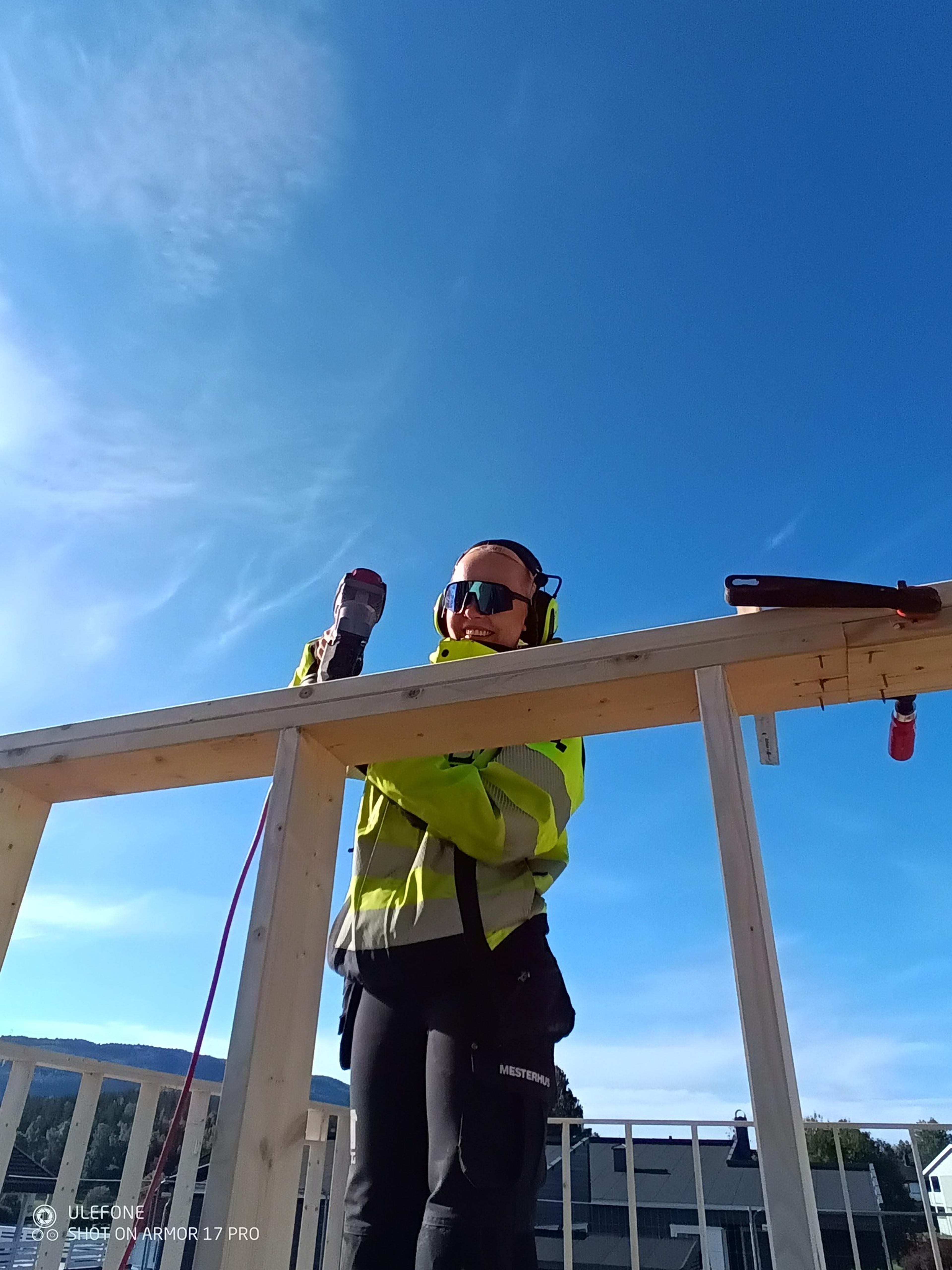 Kvinne med hørselsvern og spikerpistol 