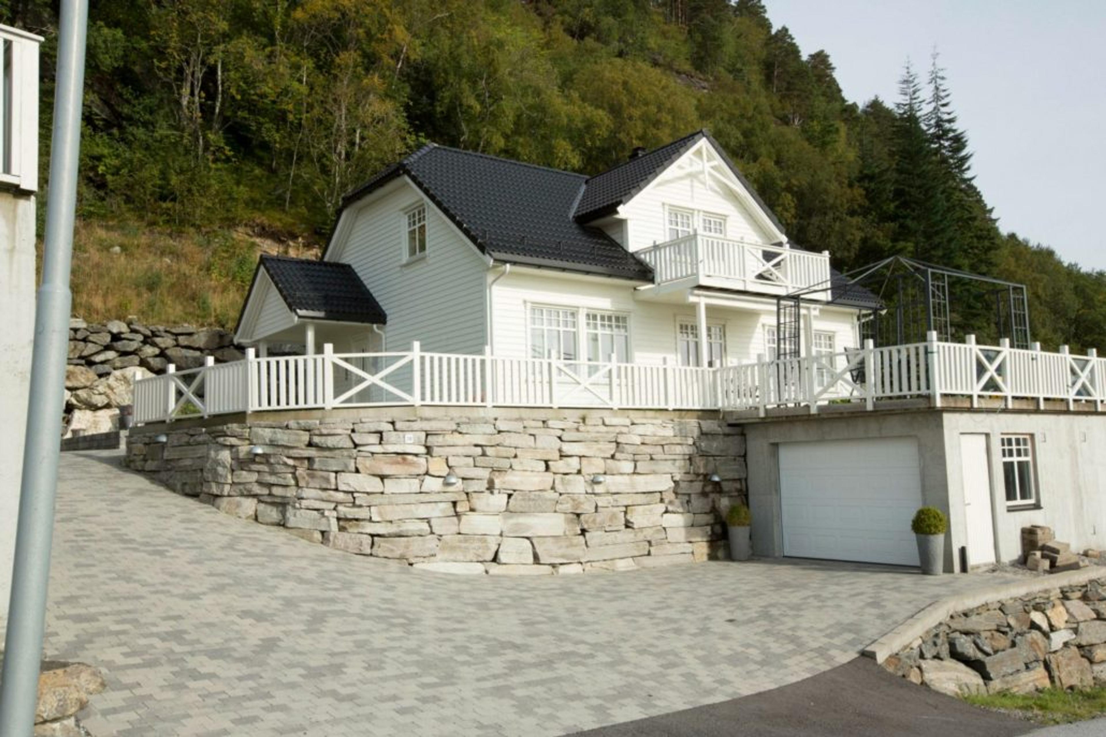 Hvit enebolig på to plan med veranda og garasje