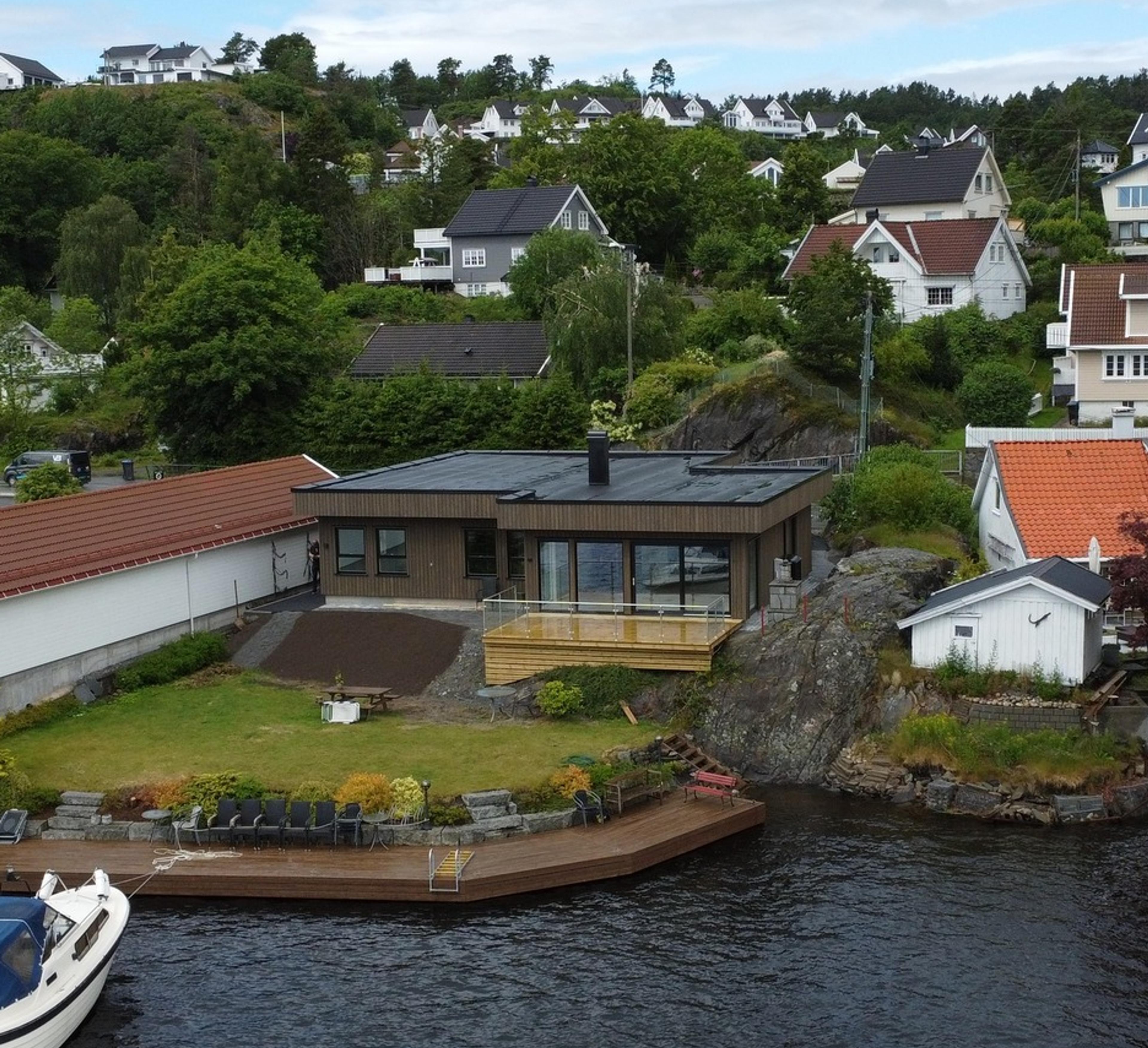 Brun ny hytte ved havet med brygge