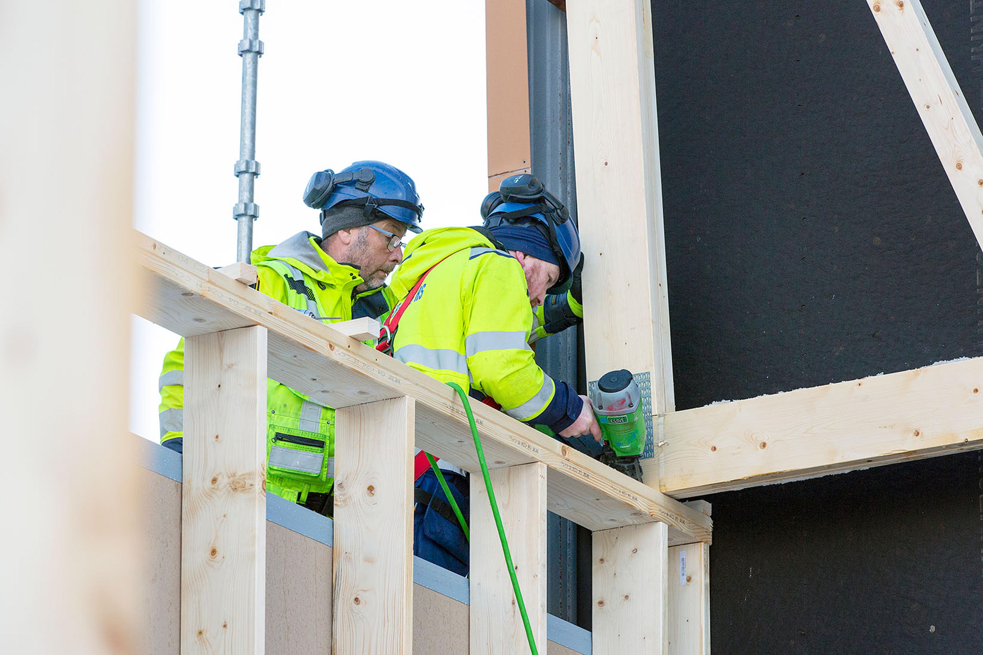 To arbeidere med hjelm som spikrer