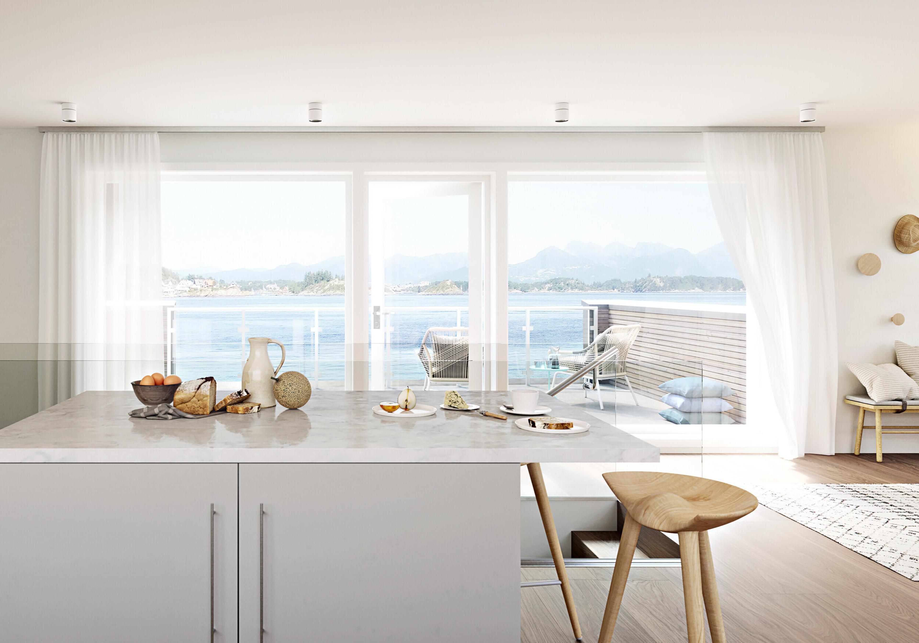 En lysegrå kjøkkenøy foran vinduer ut mot havet