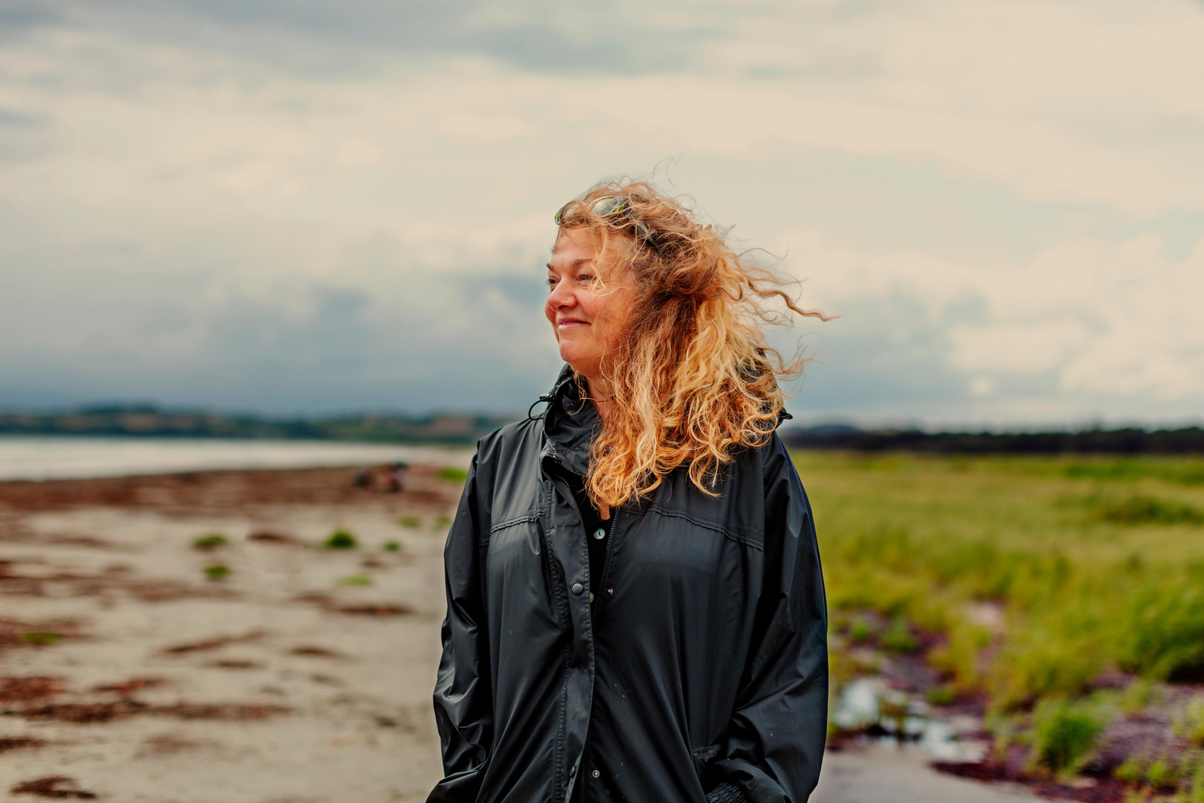 kvinne på stranden med vind i håret