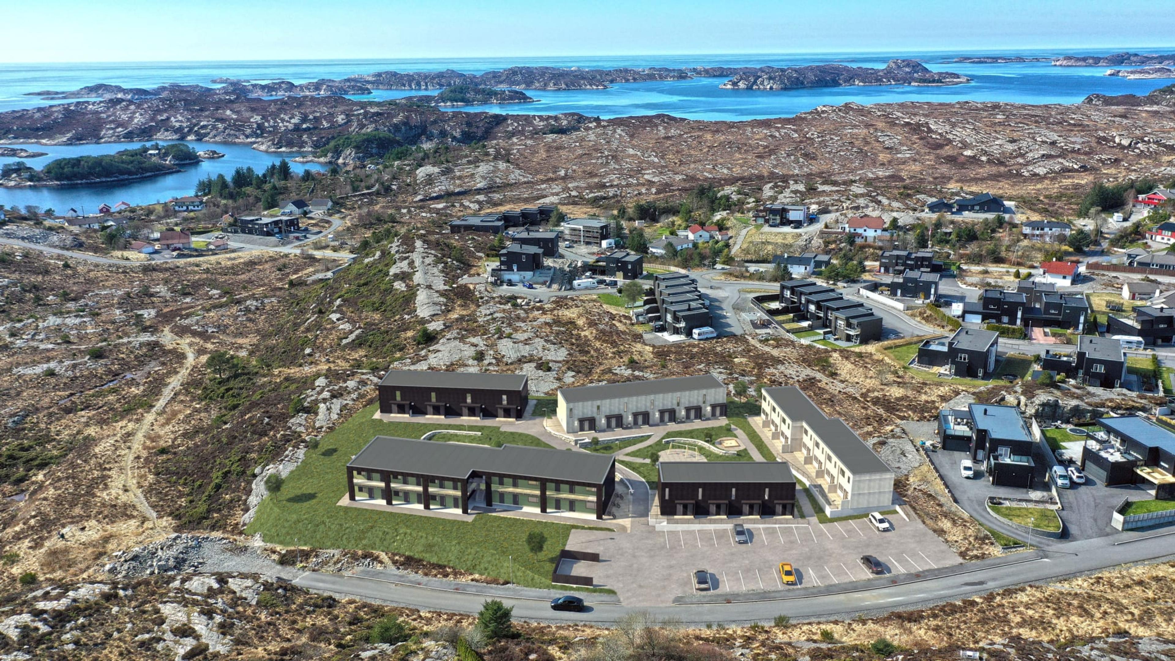 Oversiktsbilde av boligbyggene med flott terreng og sjøen like ved.