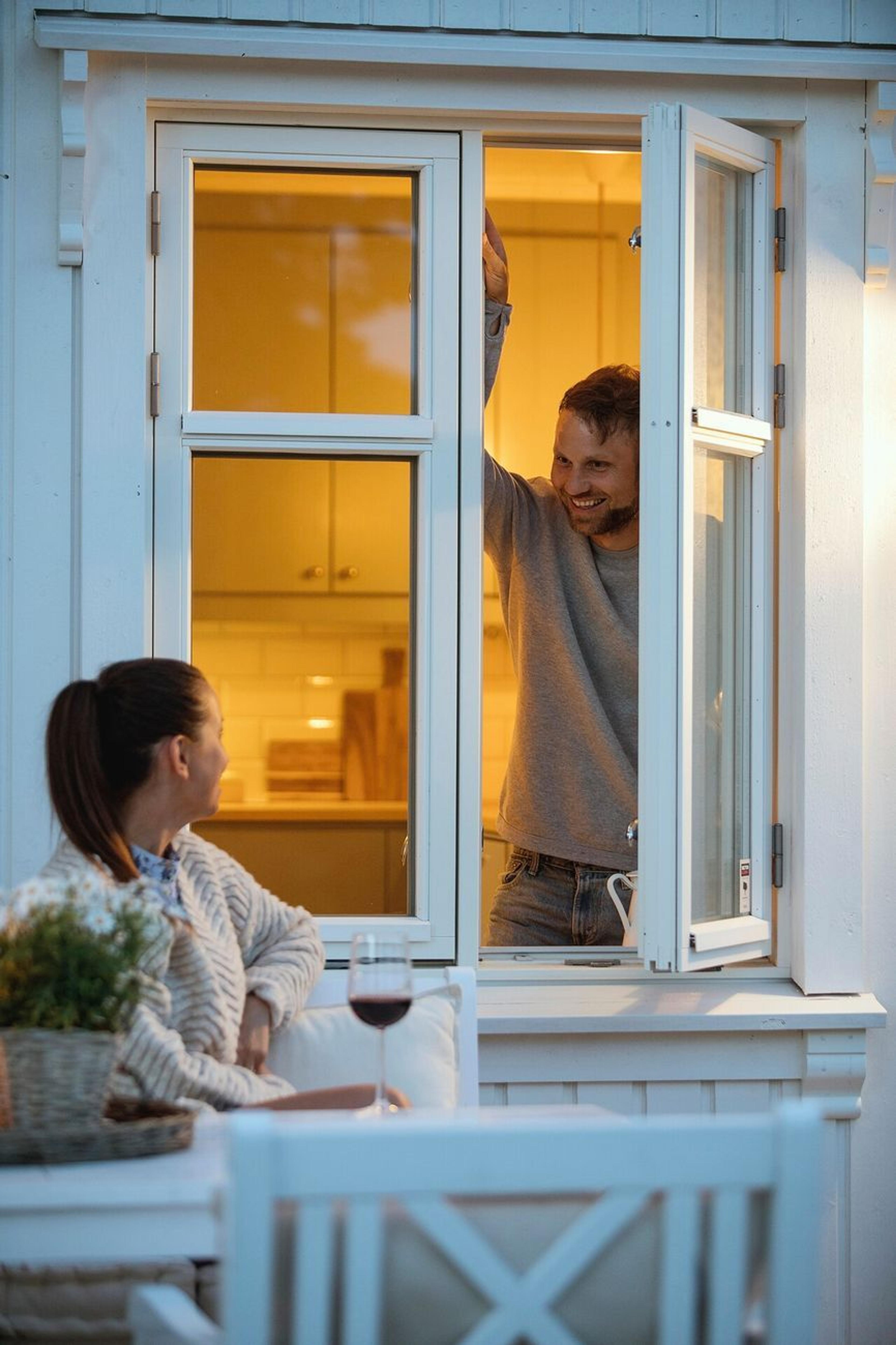 En mann åpner vinduet og prater med kona som sitter utenfor