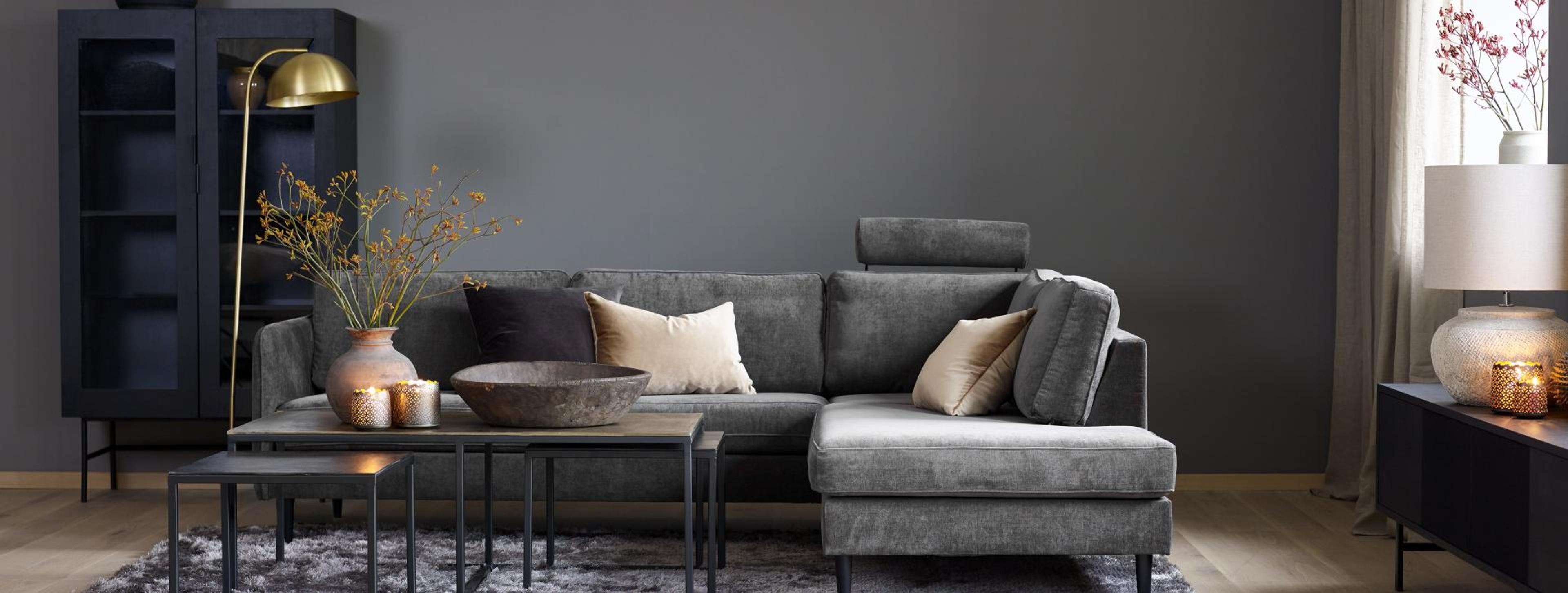 En svartmalt stue med en sort veloursofa i fokus