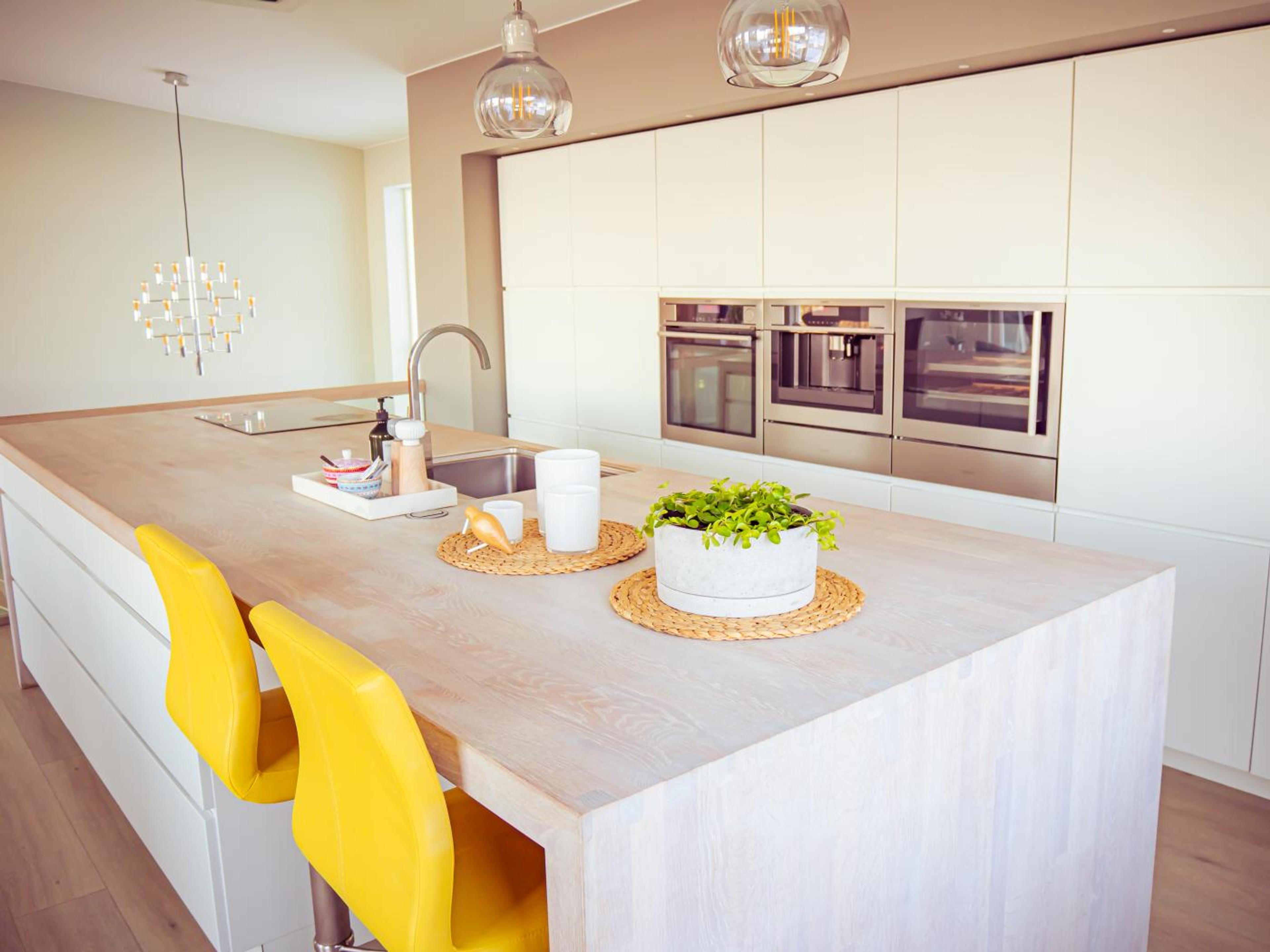 En stor kjøkkenøy med knall gule barstoler