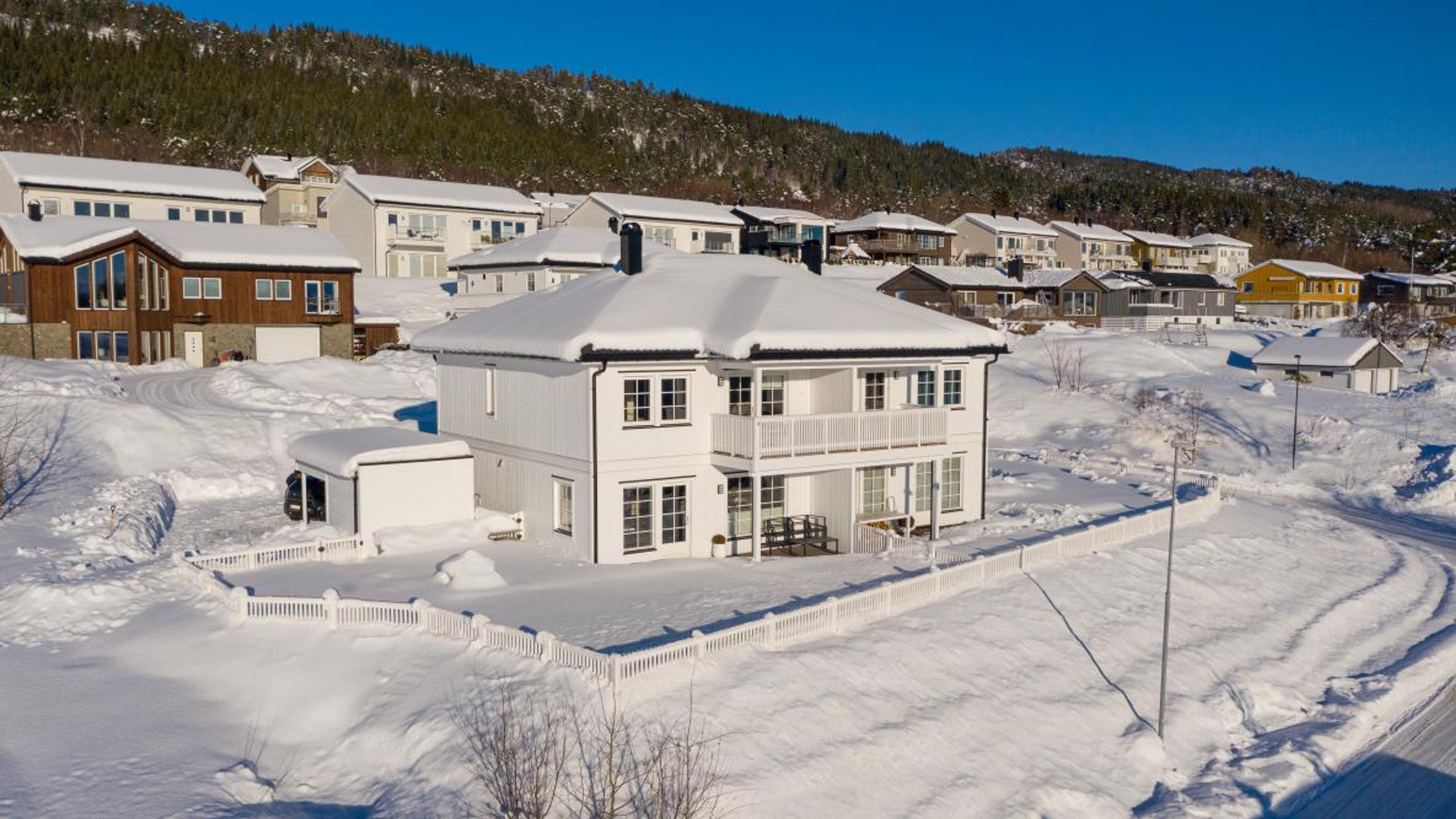 Et snødekt hvitt, klassisk hus over to etasjer