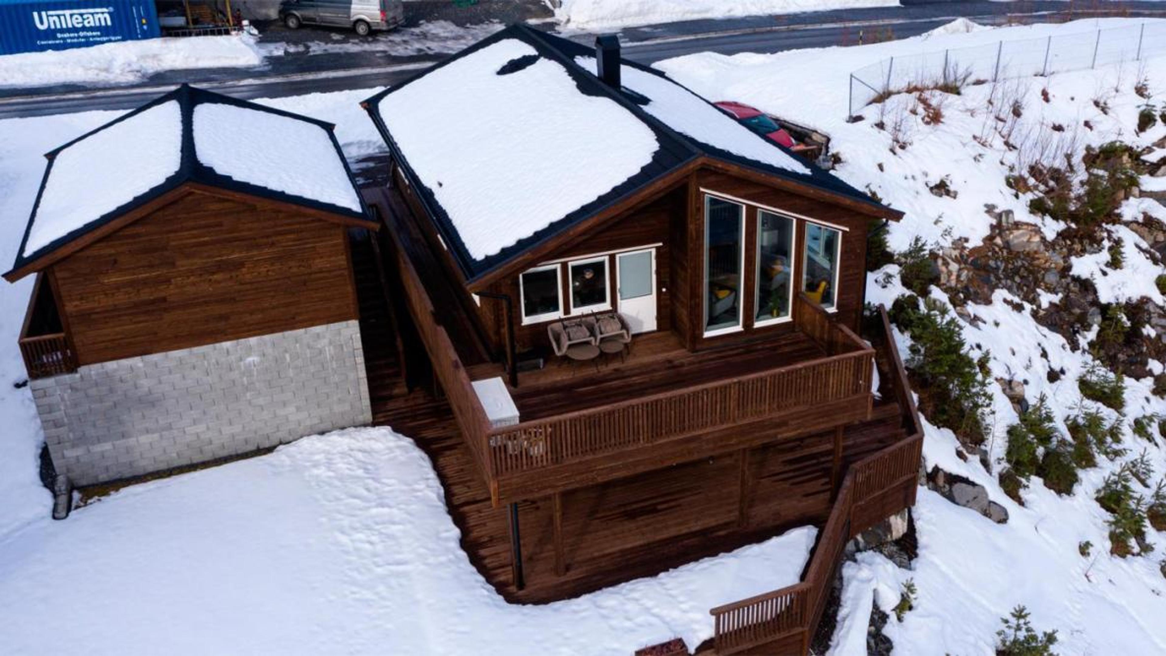 Et mørkebrunt hus over to etasjer med snø på taket