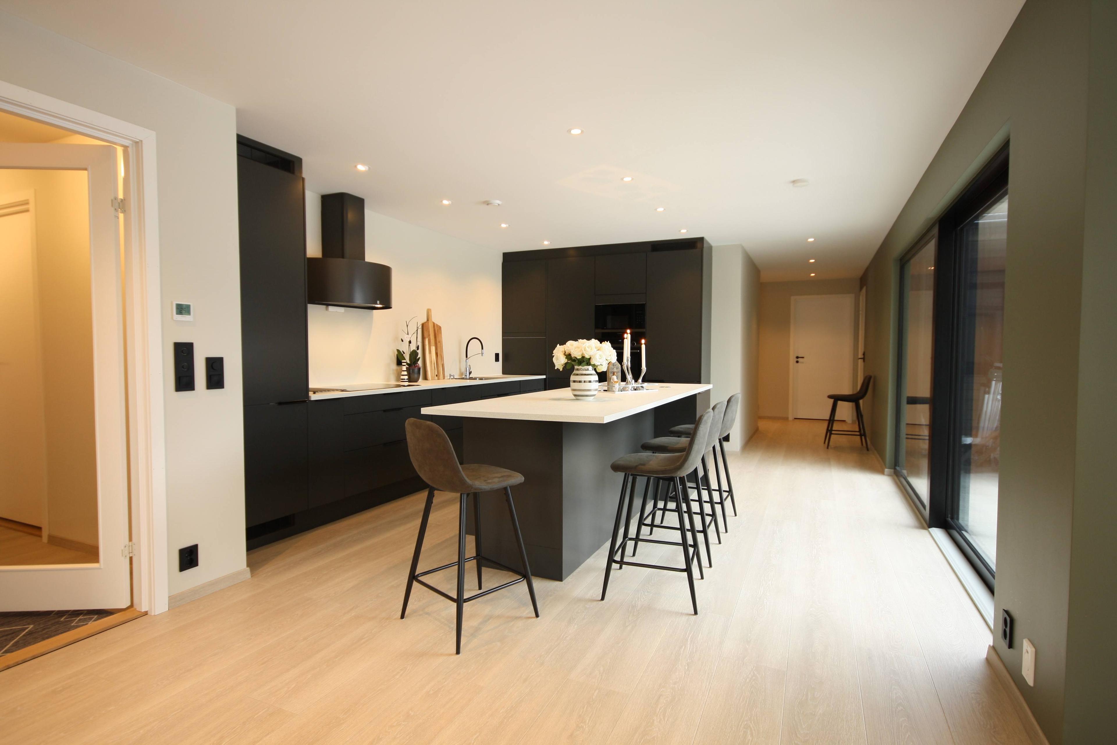 Et sort kjøkken med en kjøkkenøy og fire barstoler