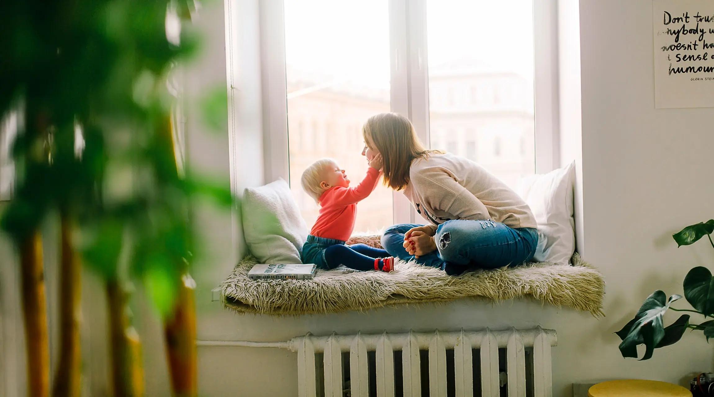 Kvinne og barn sitter i vinduskarm
