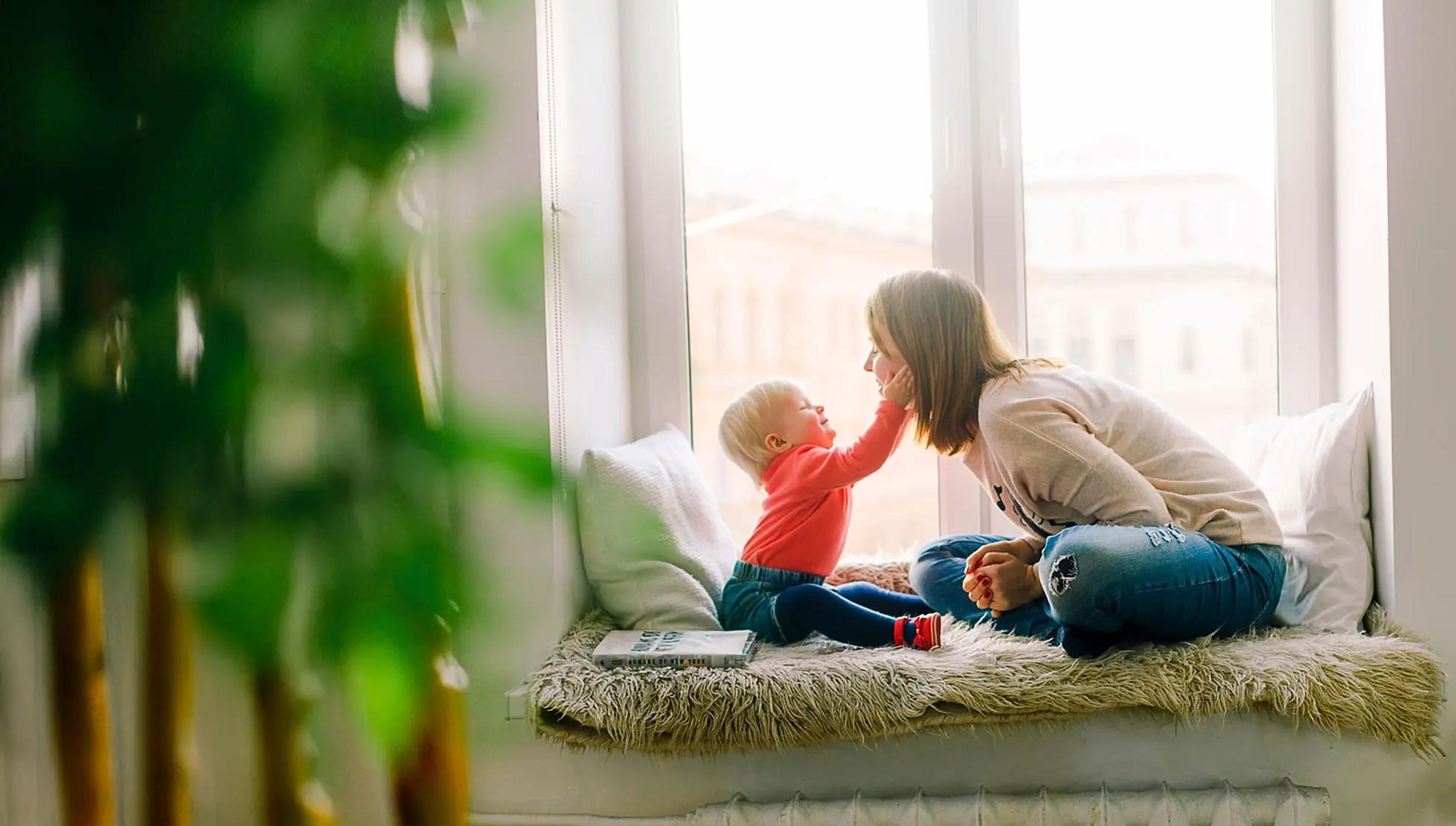 Kvinne og barn sitter i vinduskarm
