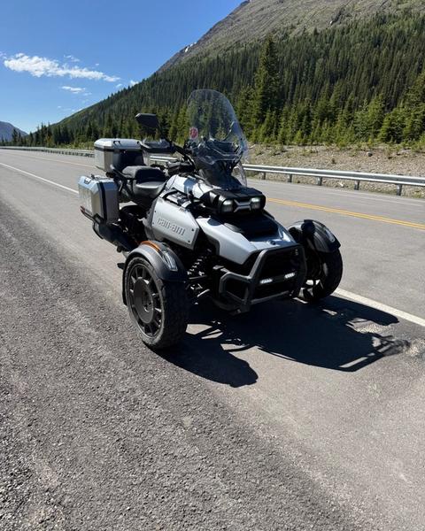 A Can-Am three-wheeler parked on an empty mountain highway in the Rockies