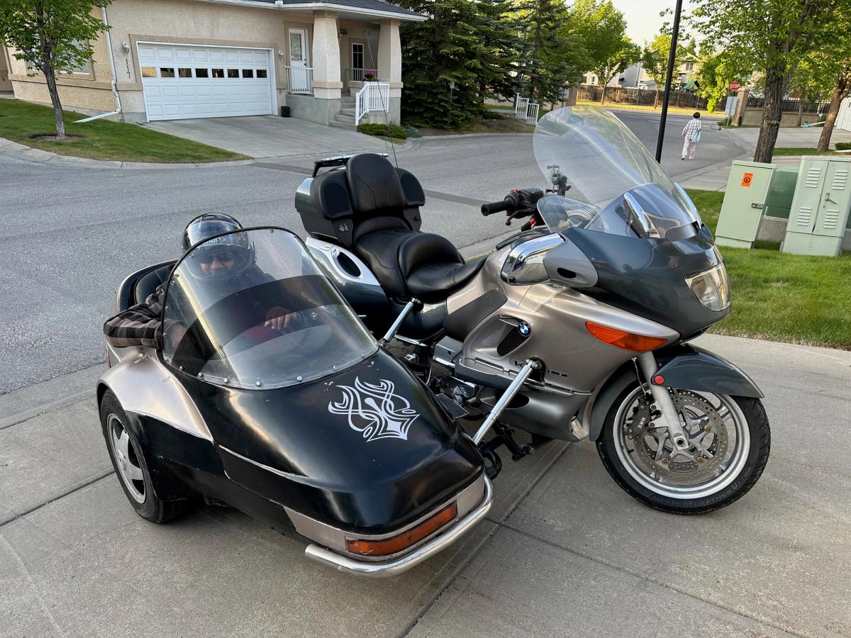Rohit's BMW motorcycle and its black sidecar in the driveway, a helmeted passenger sitting in the sidecar