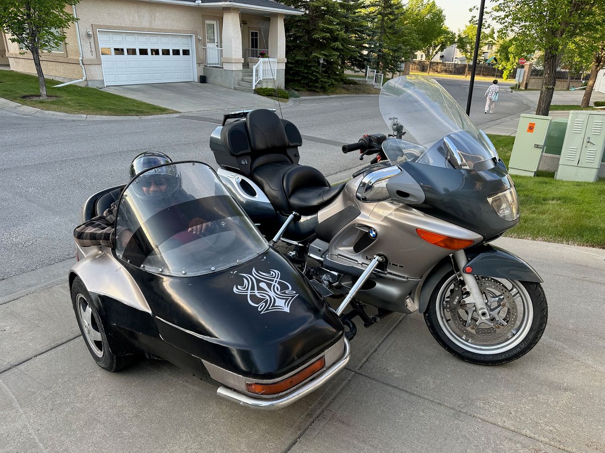 Rohit's BMW motorcycle and its black sidecar in the driveway, a helmeted passenger sitting in the sidecar