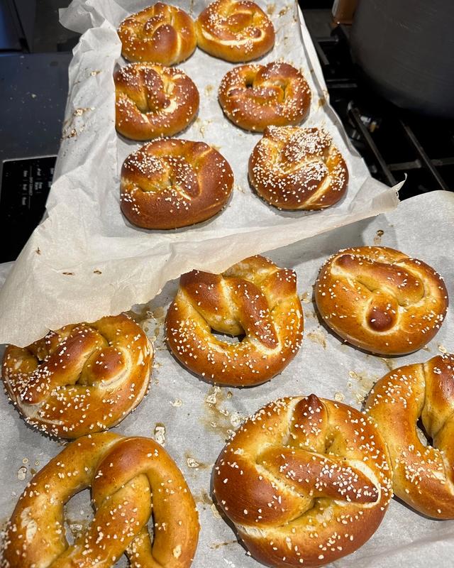 Two trays of freshly baked soft pretzels, salted, on parchment