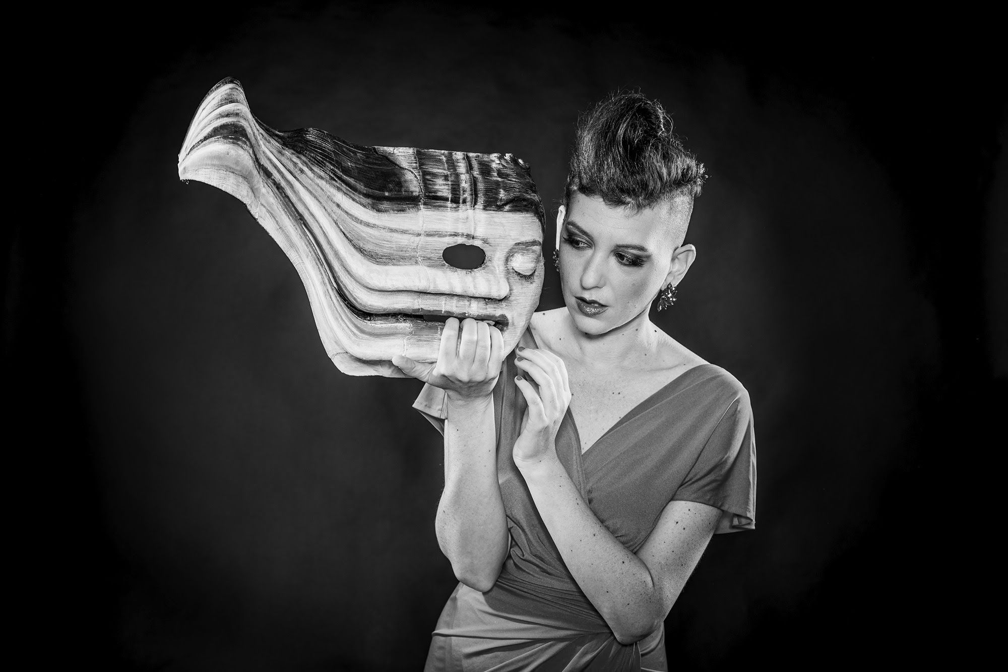 Yael Rasooly in a black-and-white portrait with a theatrical mask.