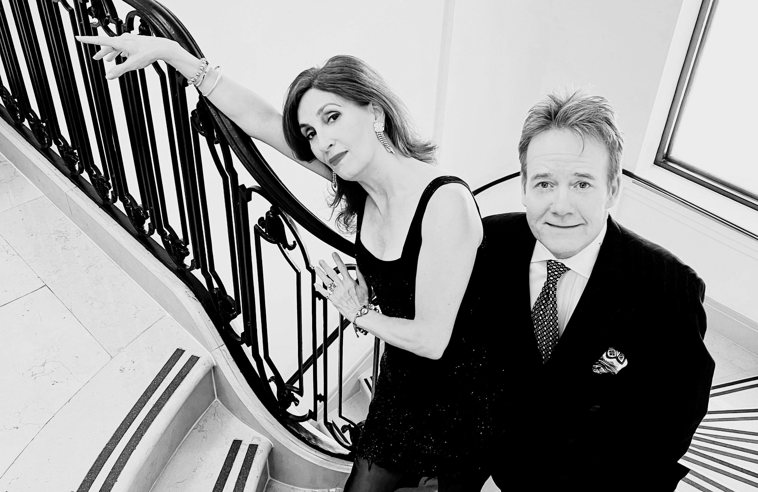 Eric Comstock and Barbara Fasano in a black-and-white portrait on a staircase.