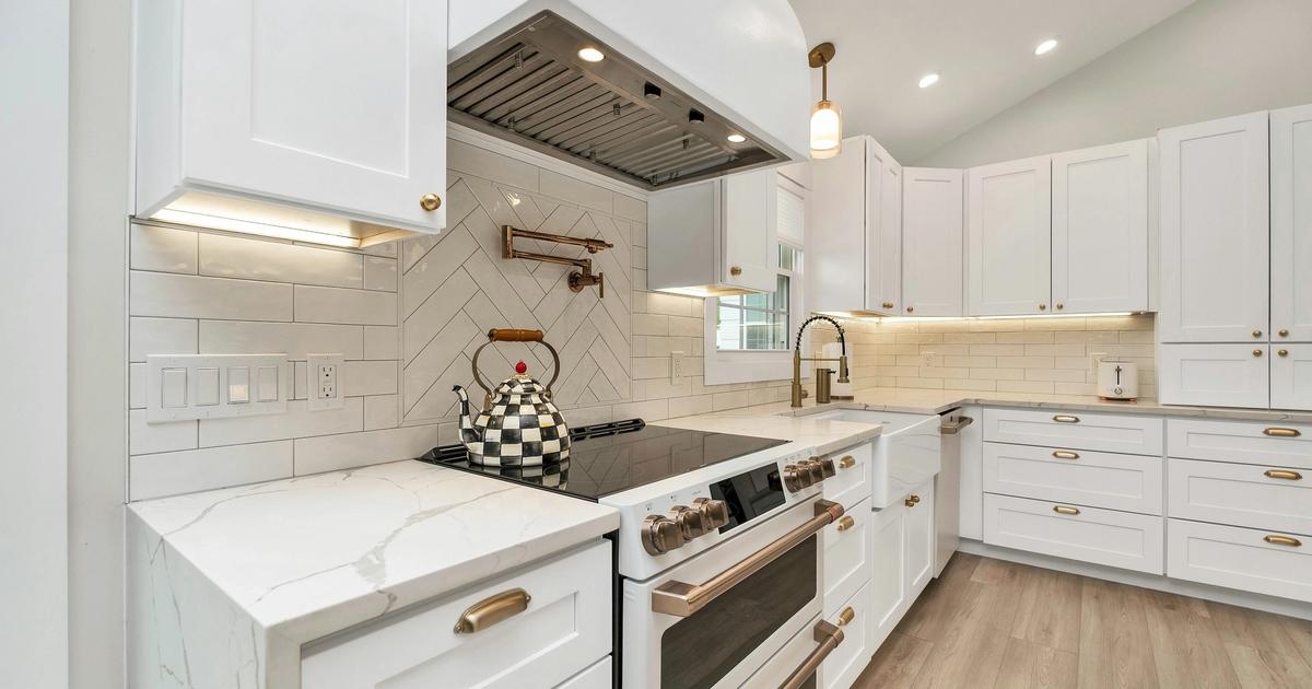 Bright white shaker kitchen with quartz countertops and gold hardware